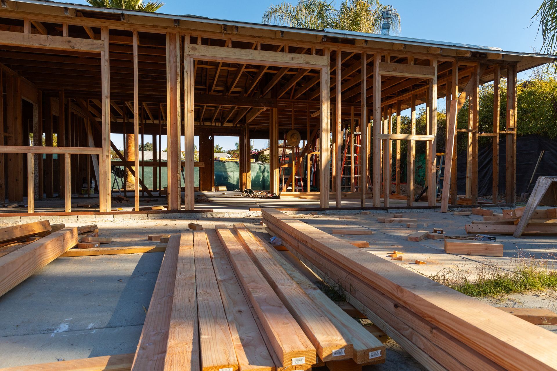 A house is being built with a lot of wood in front of it.