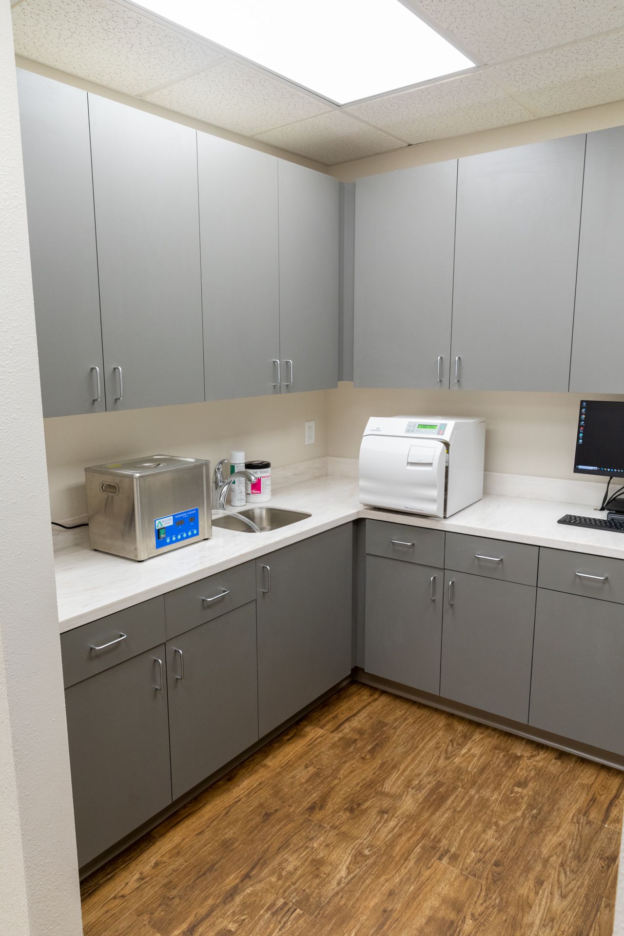 A kitchen with gray cabinets , a sink , and a sterilizer.