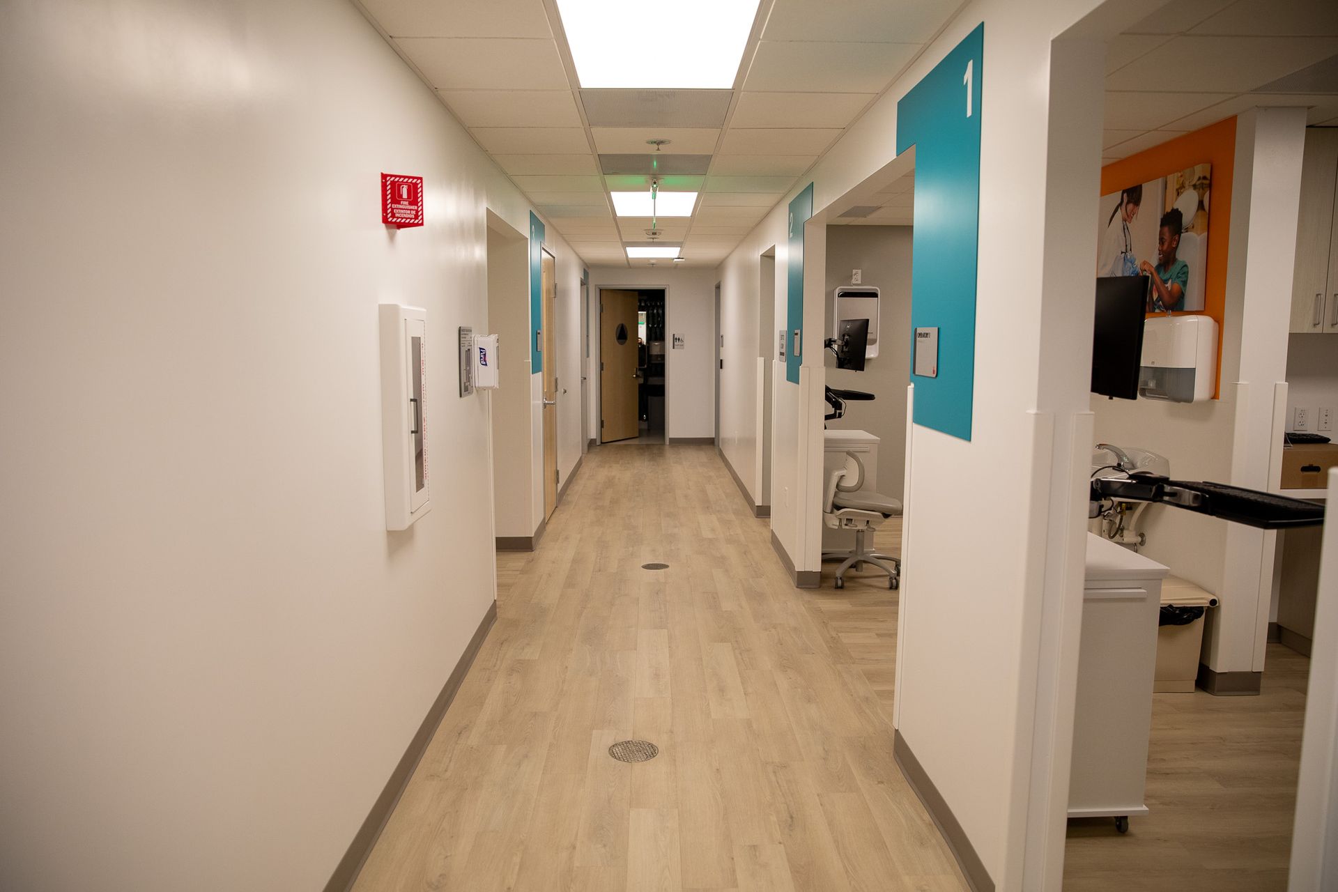 A long hallway in a hospital with wooden floors and white walls.