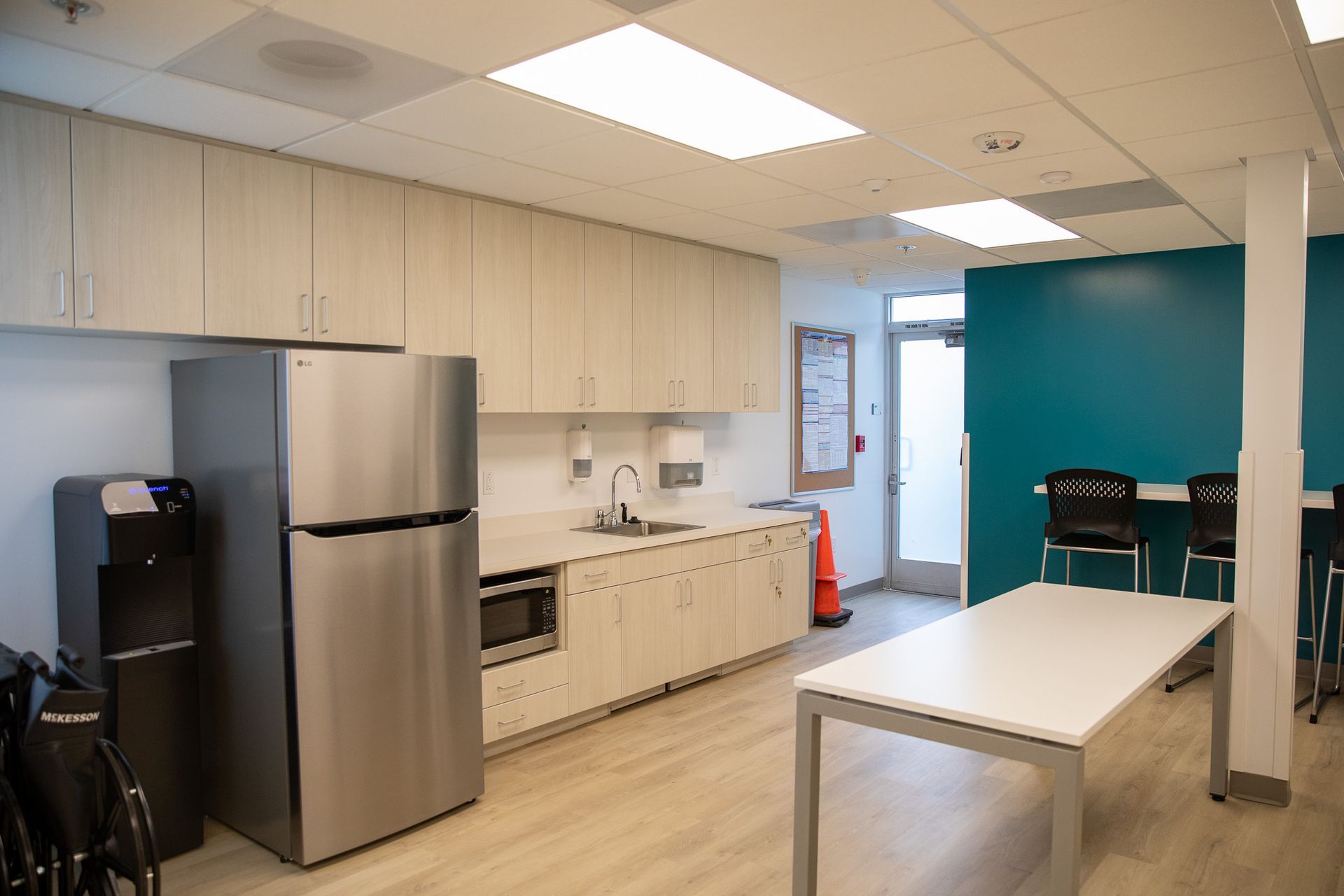 A kitchen with a refrigerator , microwave , sink , and table.