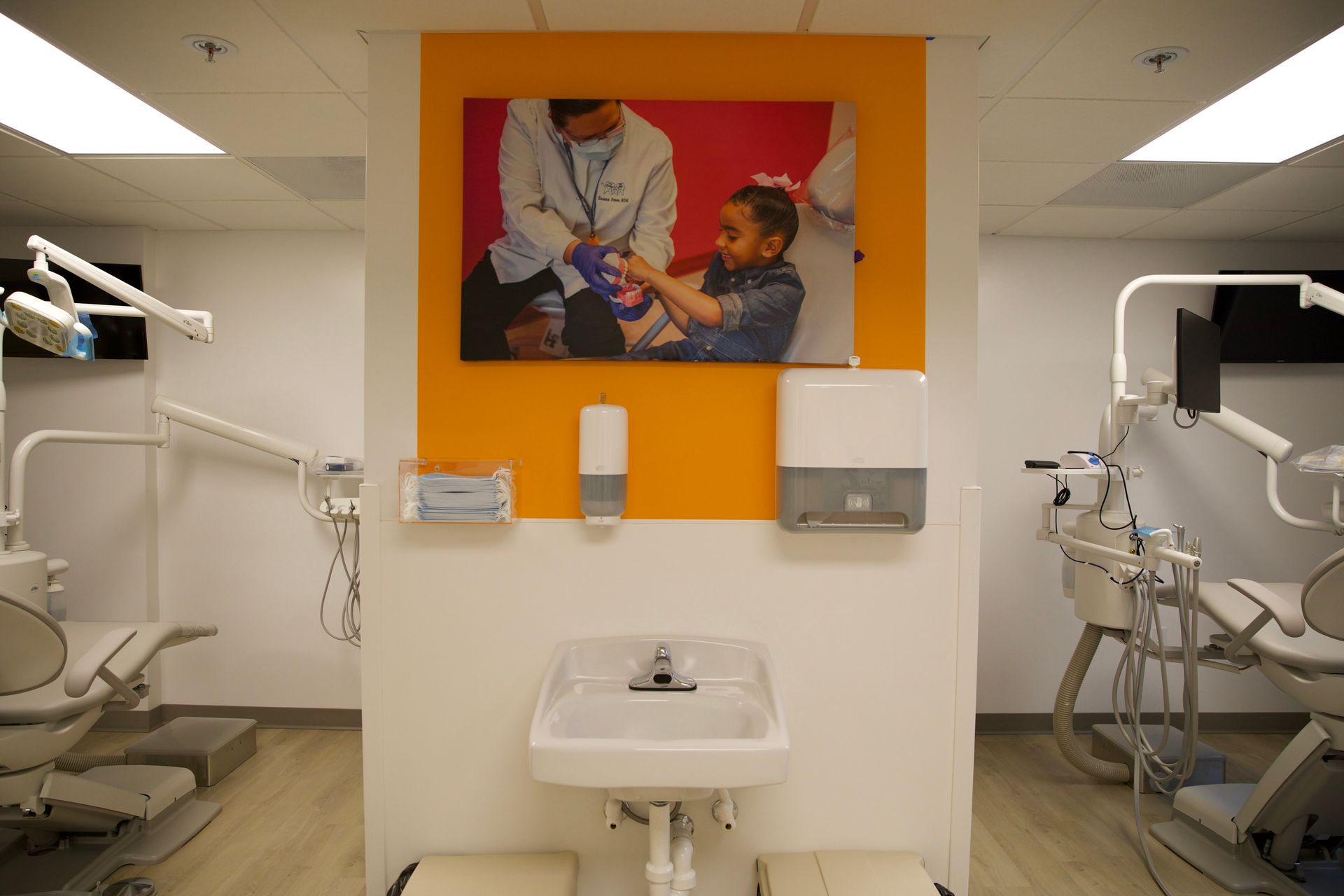 A dental office with a sink and a picture on the wall.