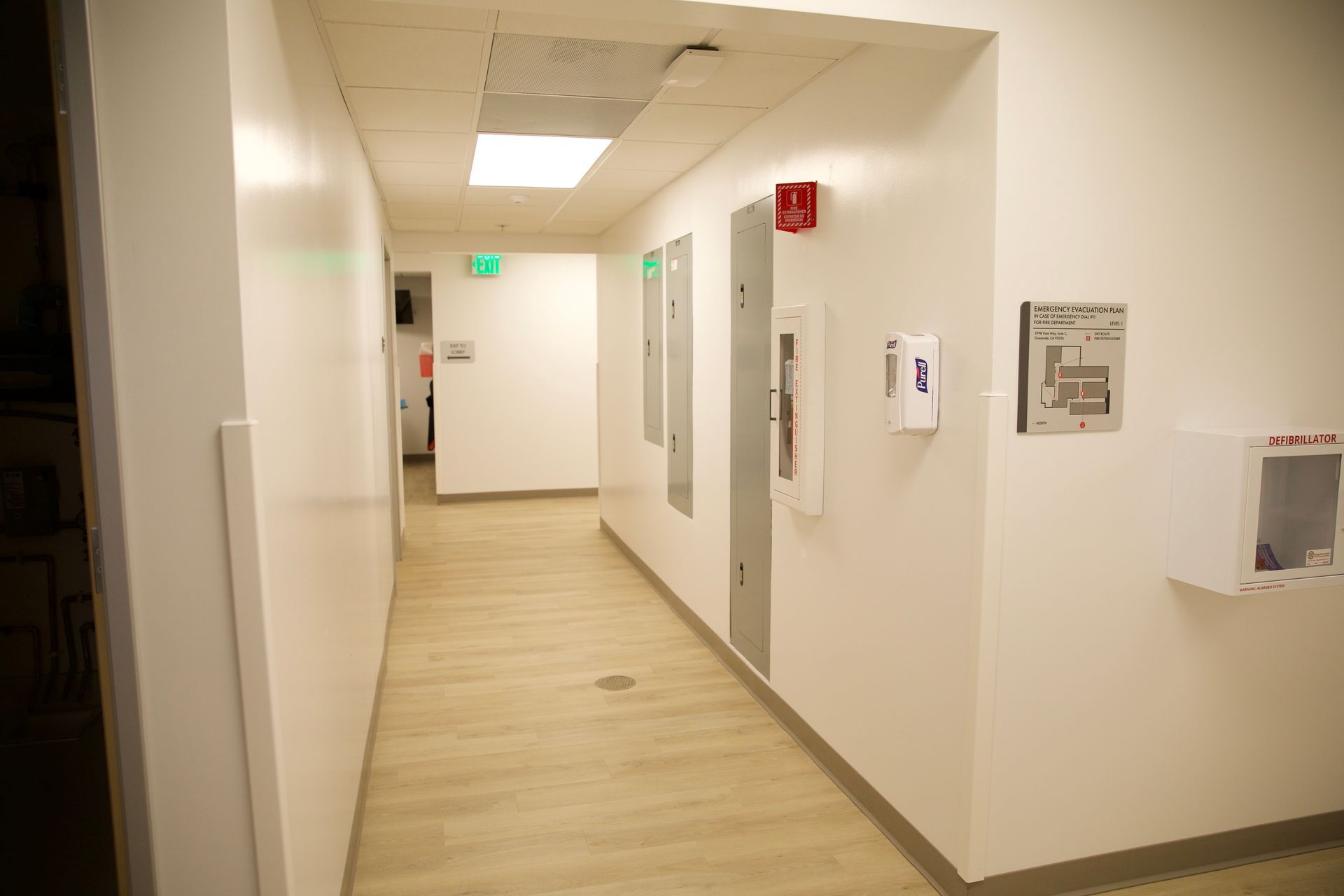 A long hallway with white walls and wooden floors in a building.