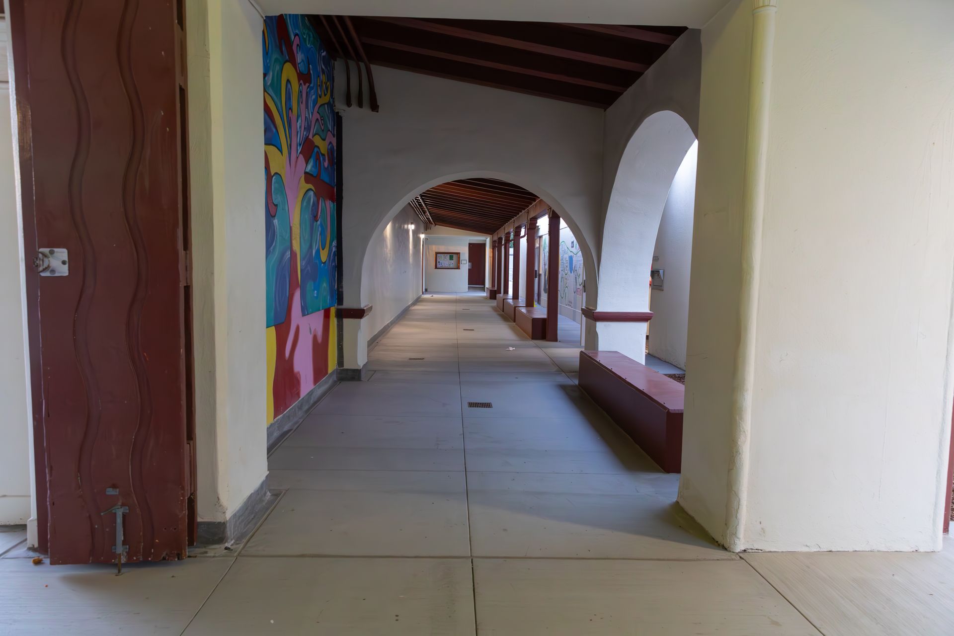 A long hallway with arches and a painting on the wall.