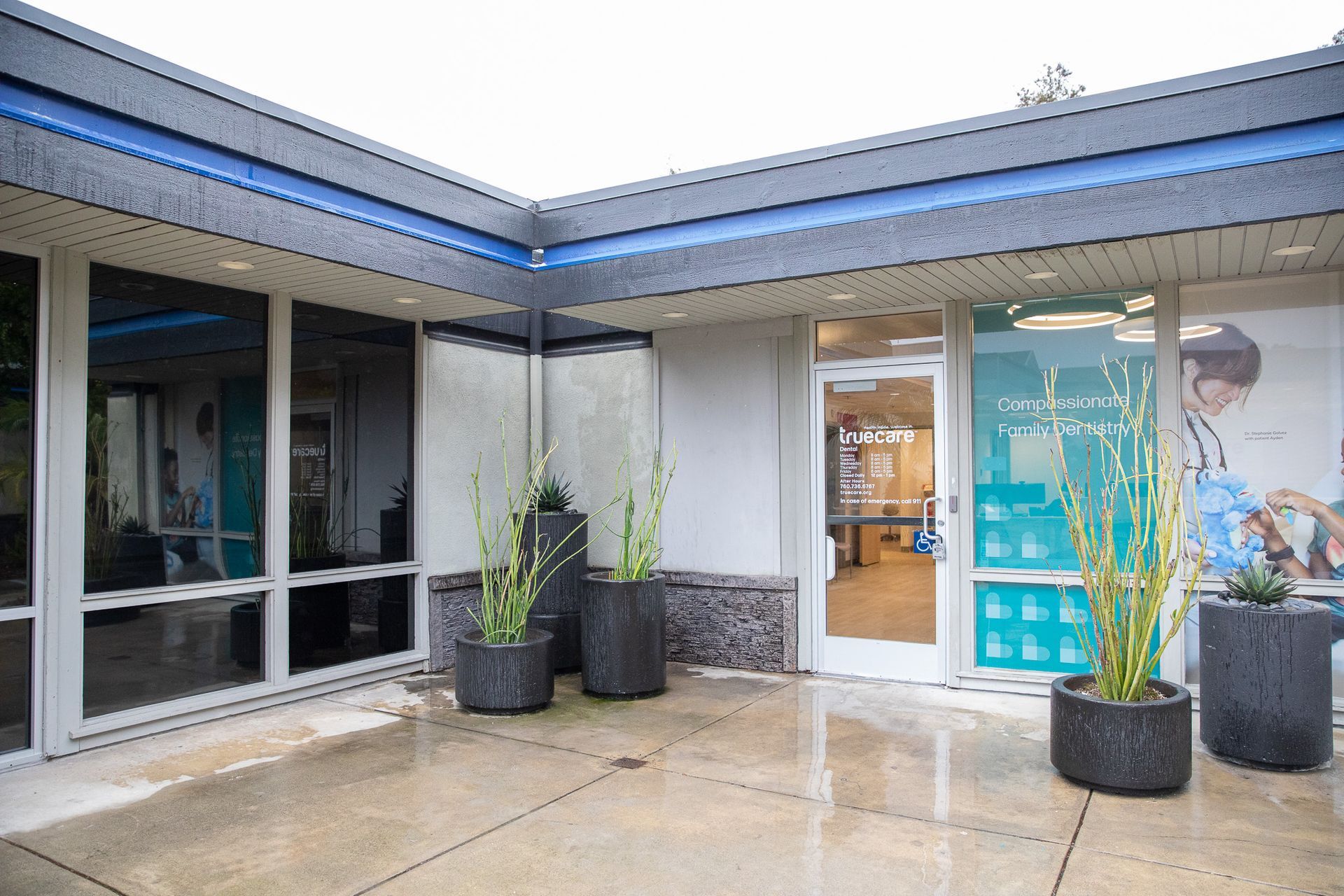 A building with a lot of windows and potted plants in front of it.