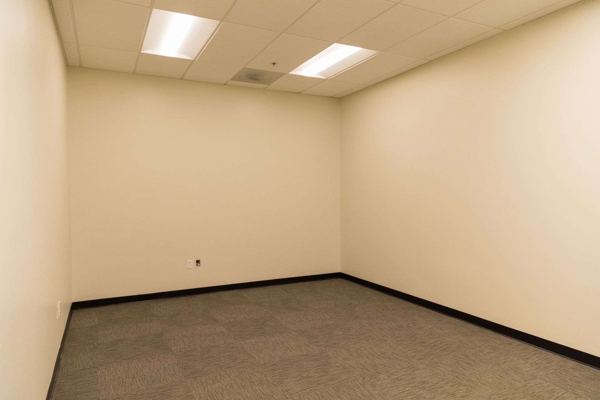 An empty room with a carpeted floor and white walls.
