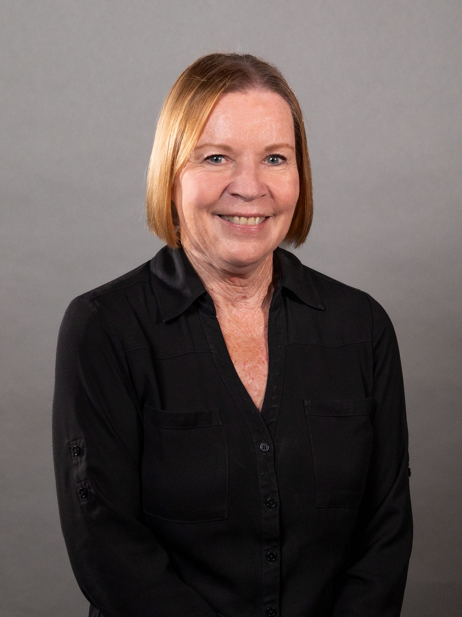 The woman is wearing a black shirt and smiling for the camera.