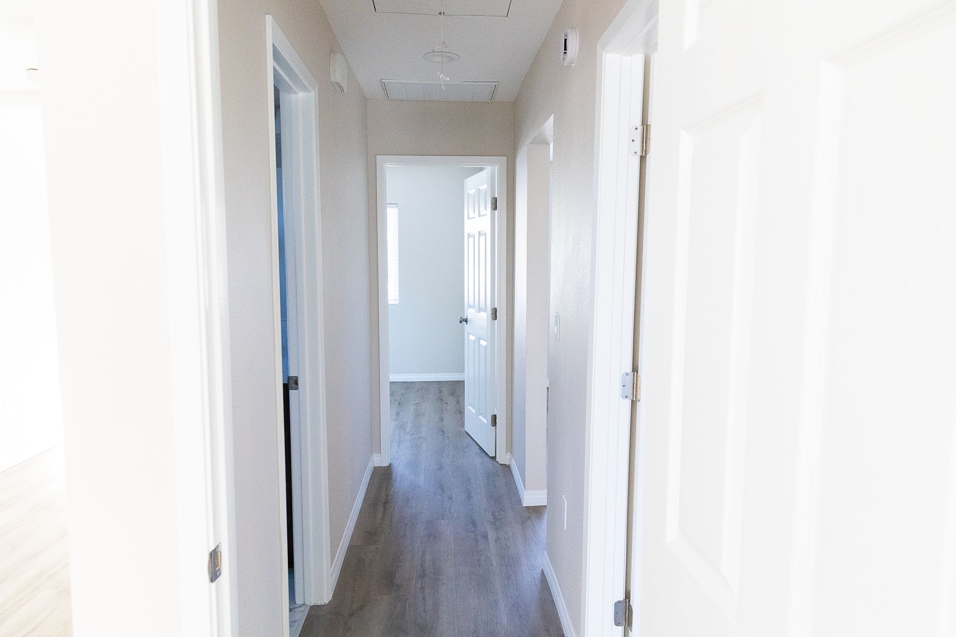 A long hallway in a house with hardwood floors and white walls.