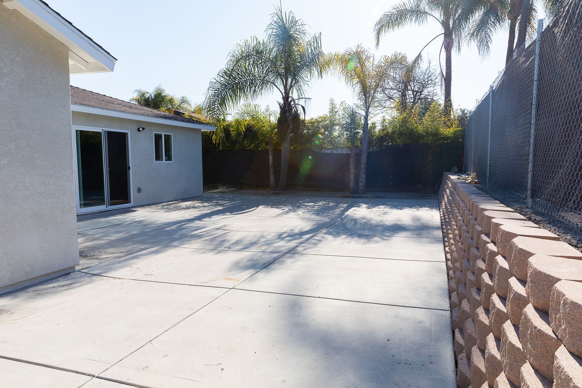A driveway leading to a house with palm trees in the background
