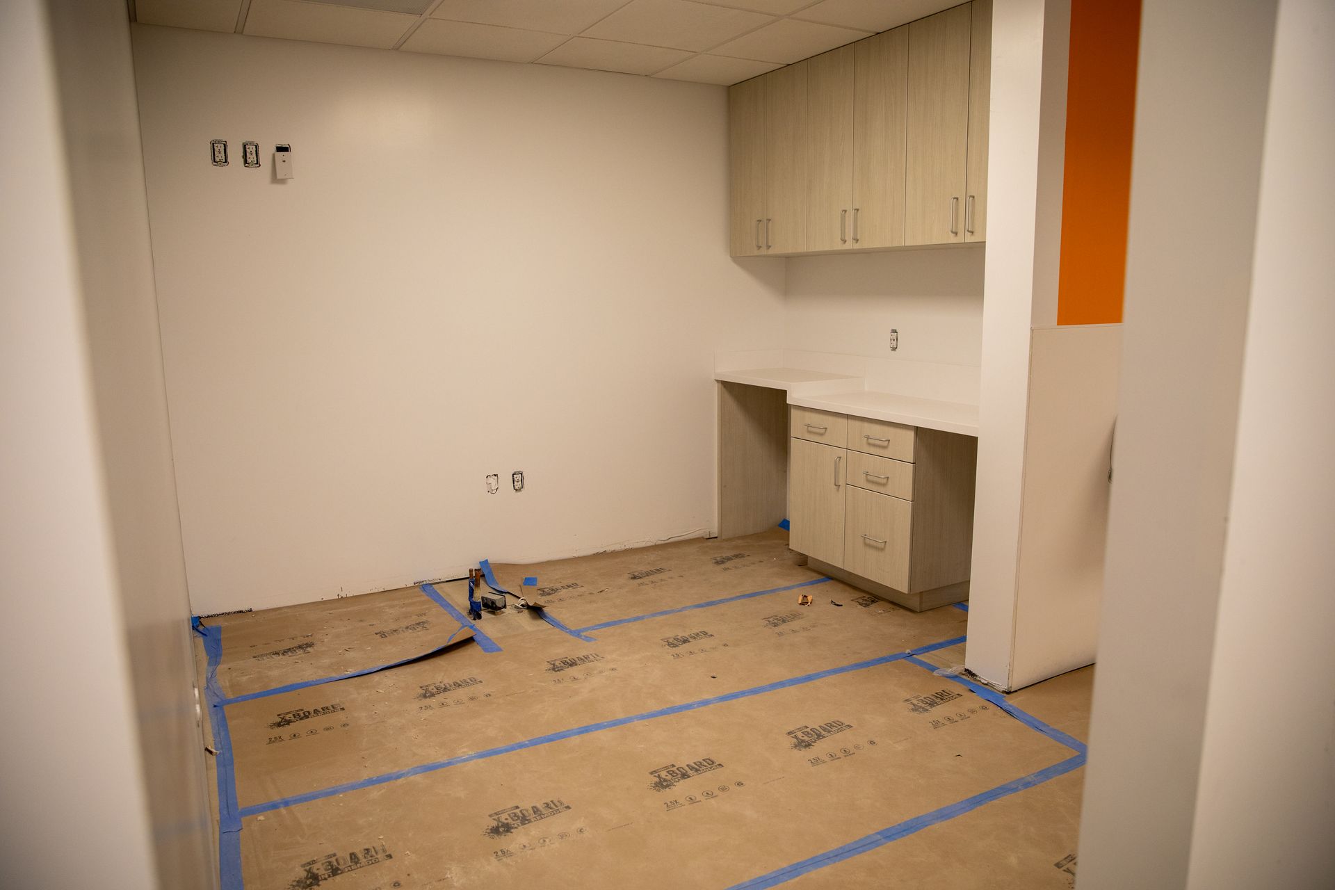 An empty room with blue tape on the floor and cabinets.