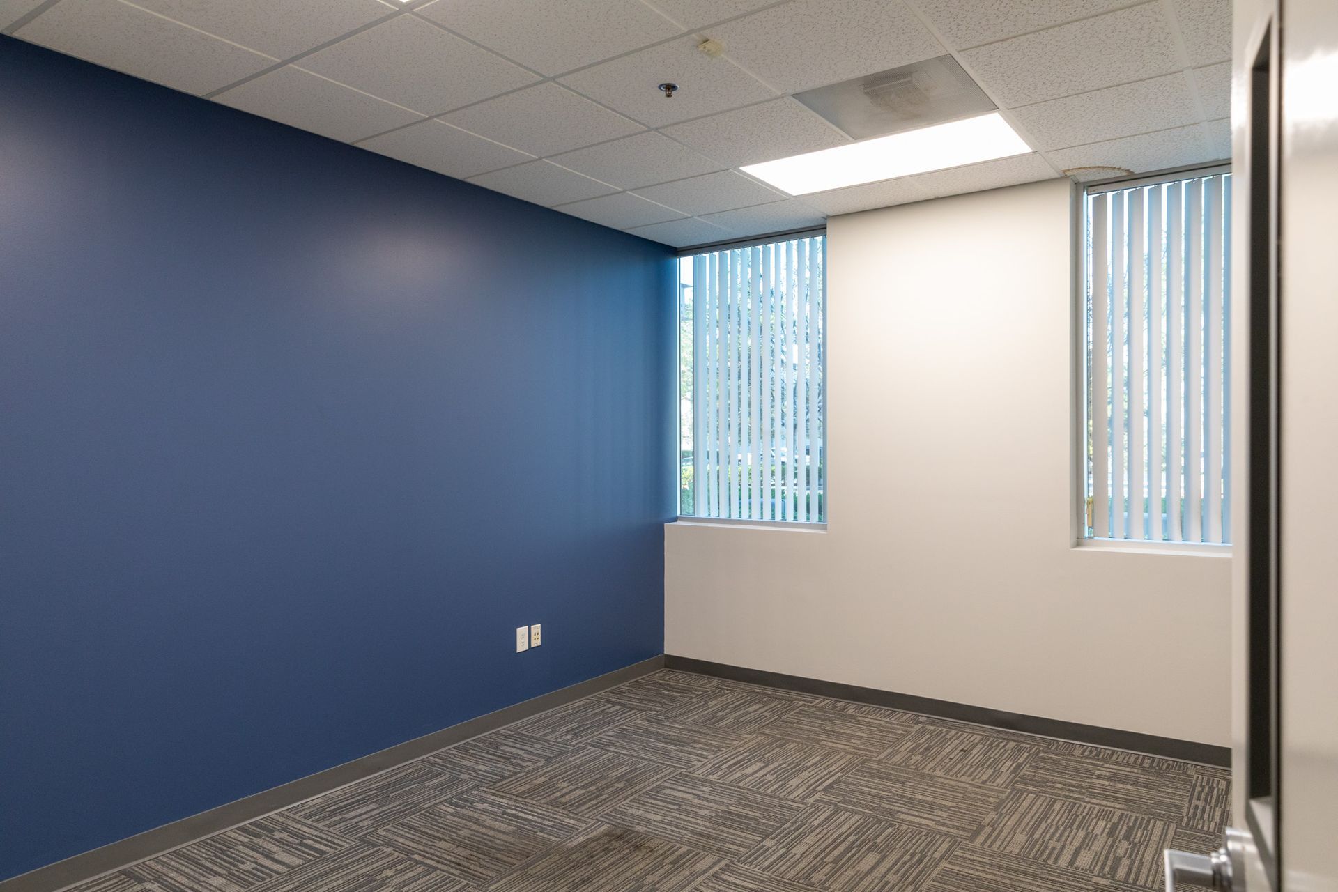 An empty room with blue walls and a window.