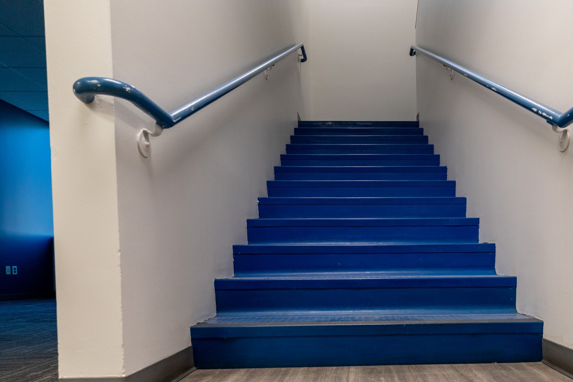 A set of blue stairs leading up to a white wall.