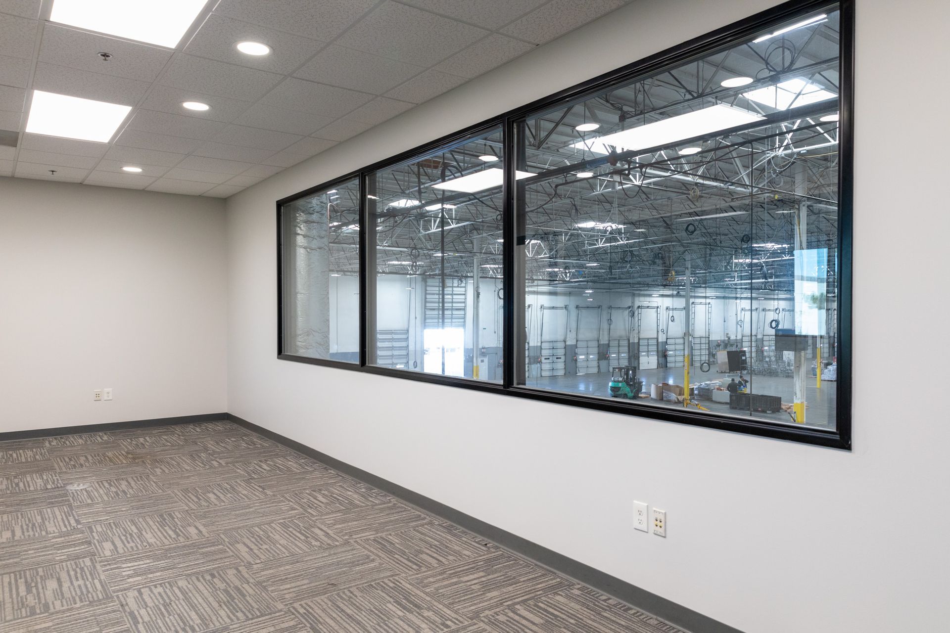 An empty room with a lot of windows and a carpeted floor.