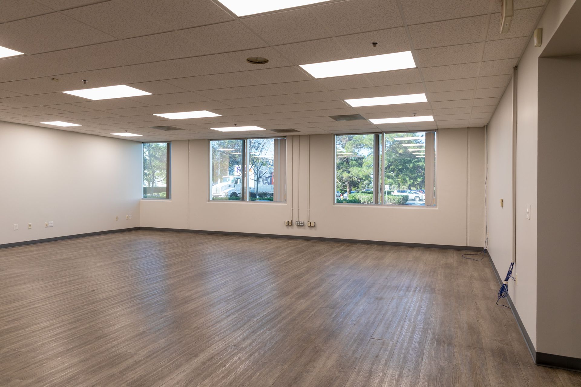 A large empty room with hardwood floors and lots of windows.