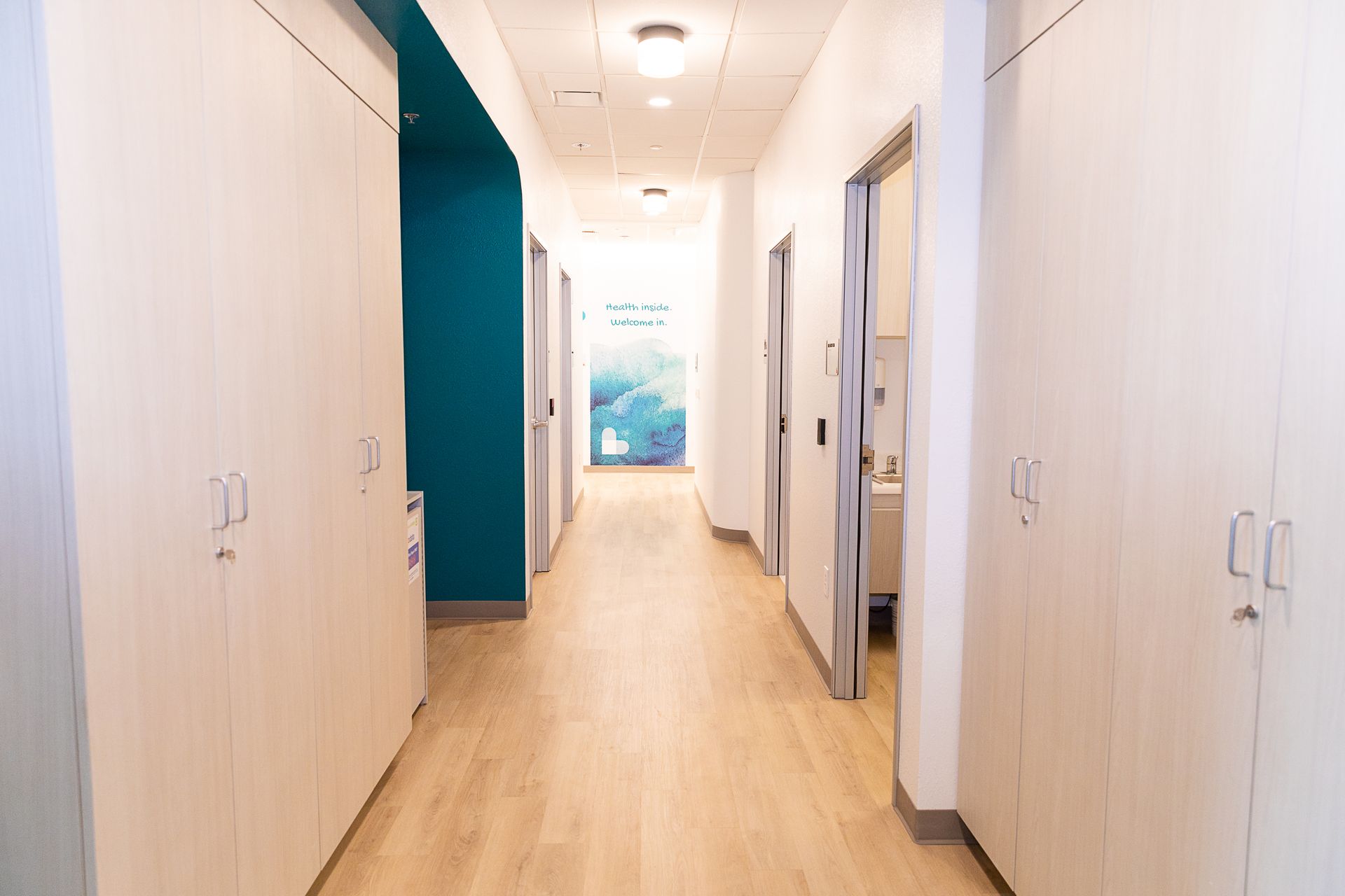A long hallway with wooden floors and cabinets in a hospital.
