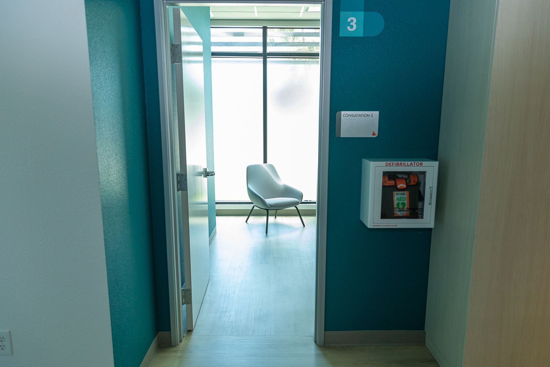 A waiting room with a chair and a box on the wall.