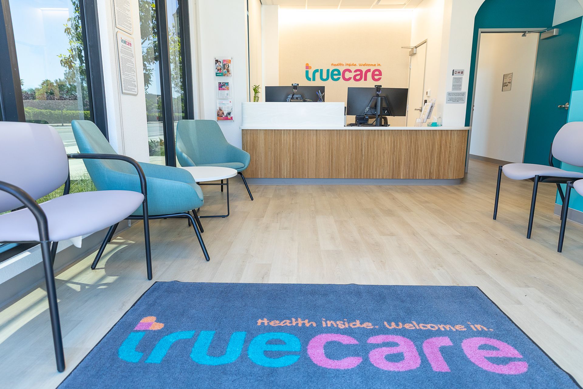 A waiting room with chairs and a rug that says truecare.