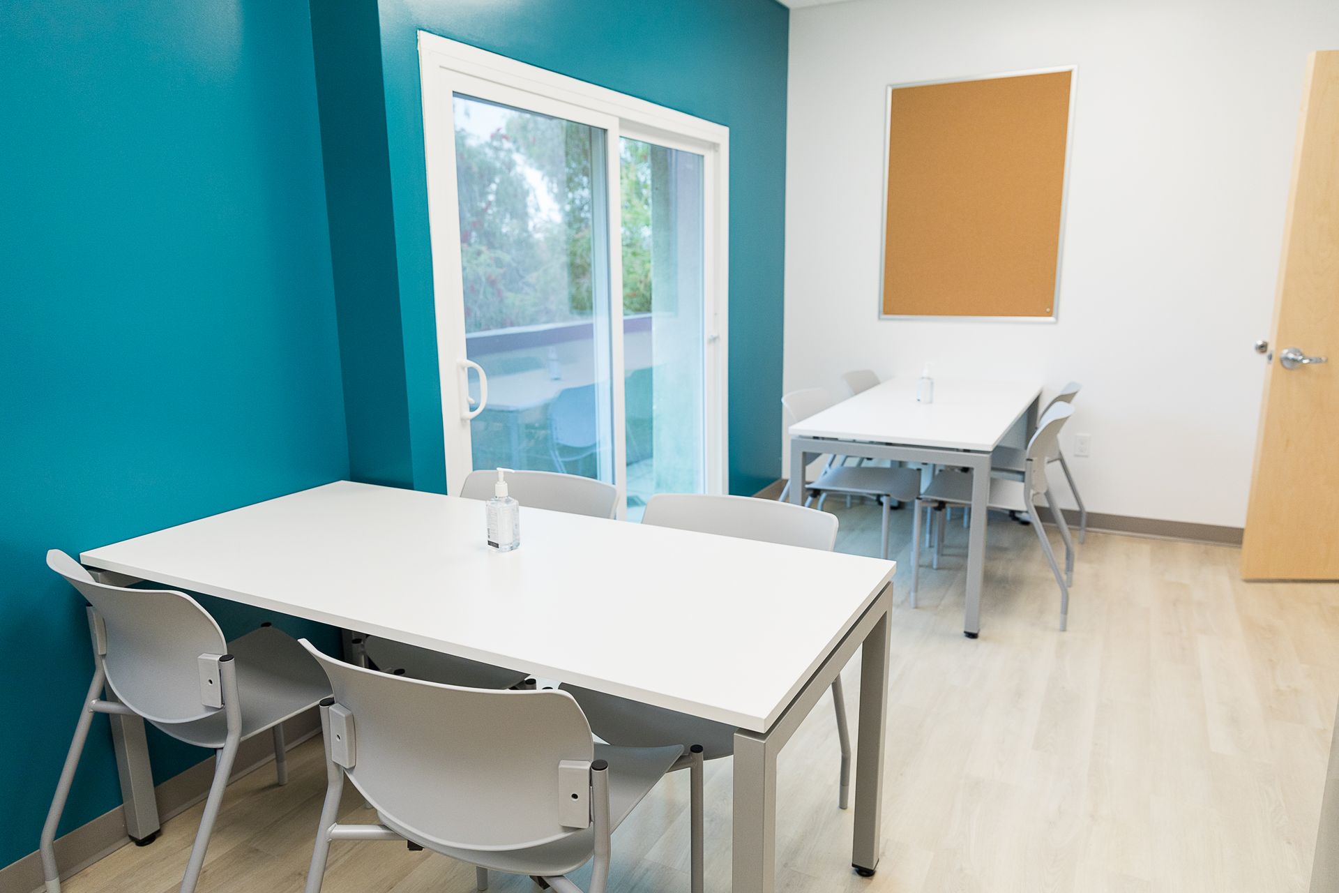 A room with a table and chairs and a sliding glass door.