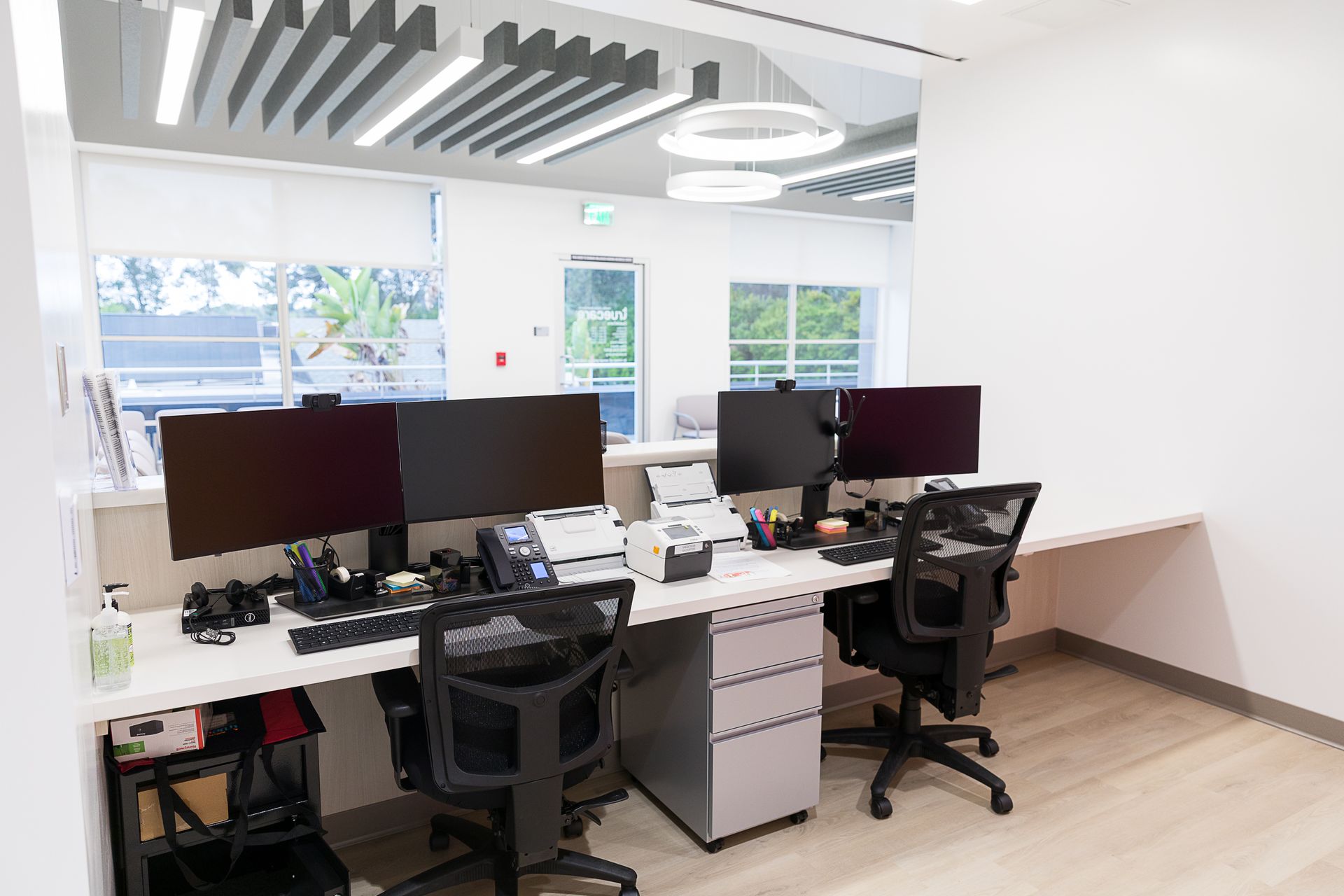 A row of desks with computers and chairs in an office.