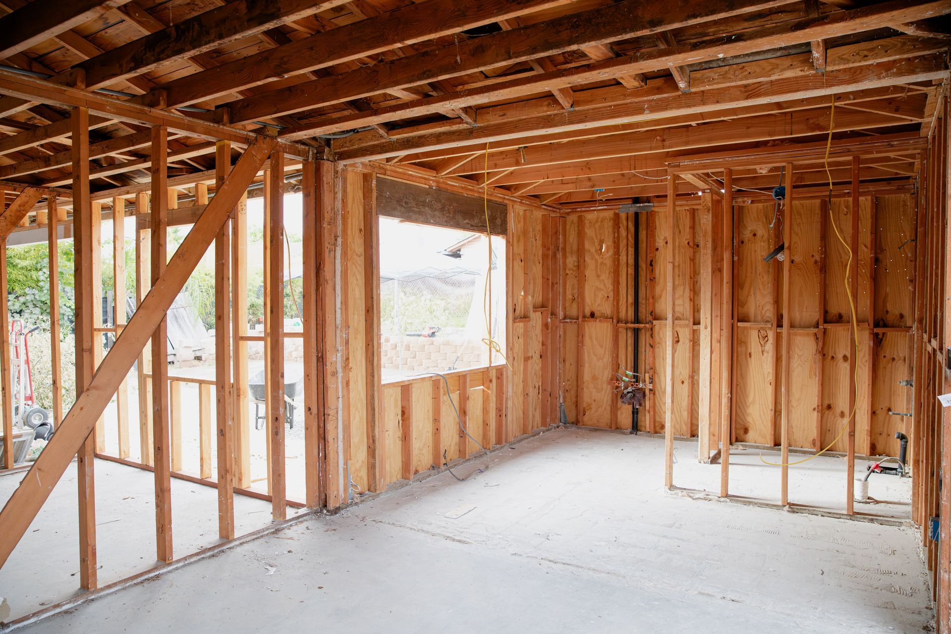 An empty room with wooden beams and a window in a house under construction.