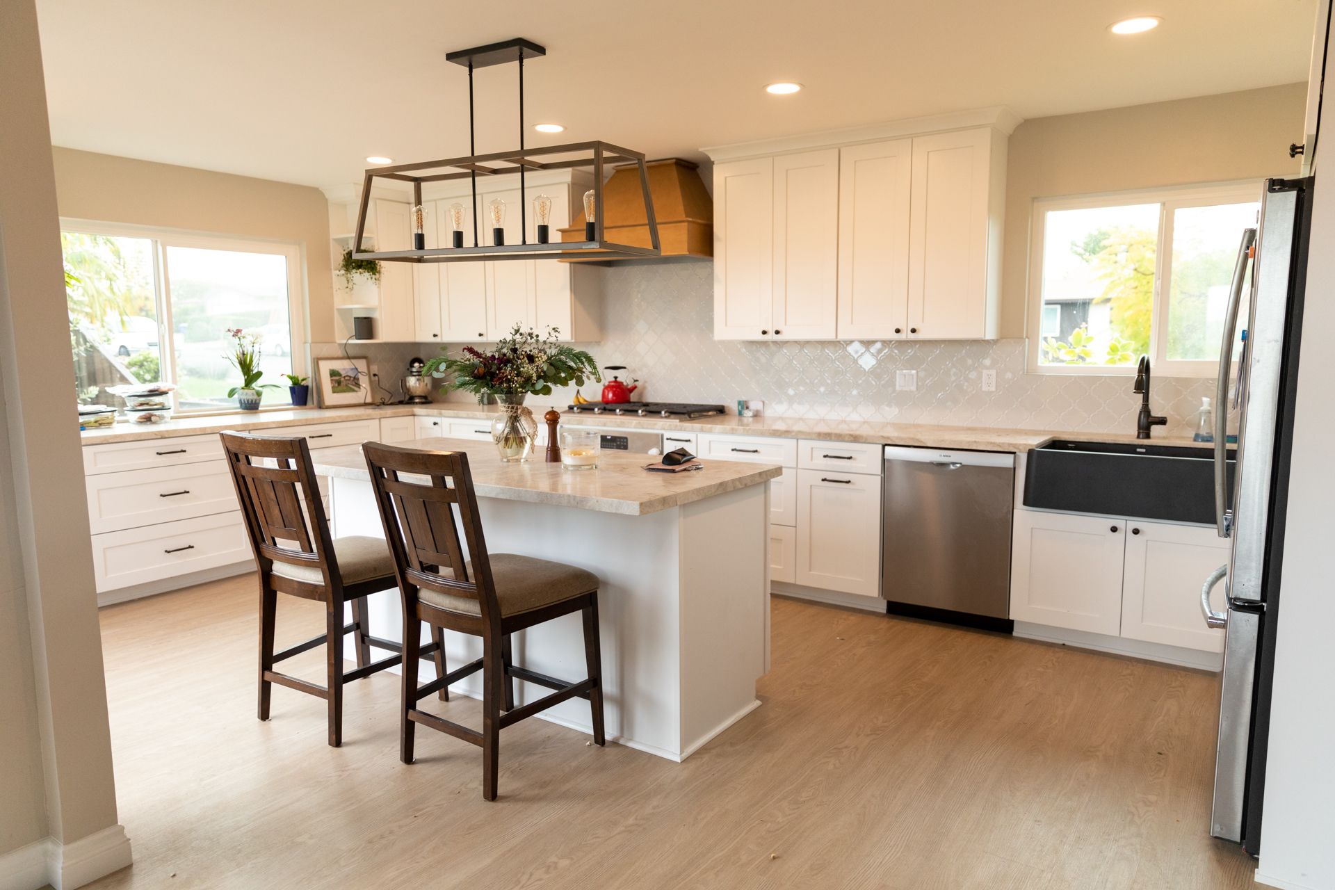 A kitchen with white cabinets , stainless steel appliances , and a large island.