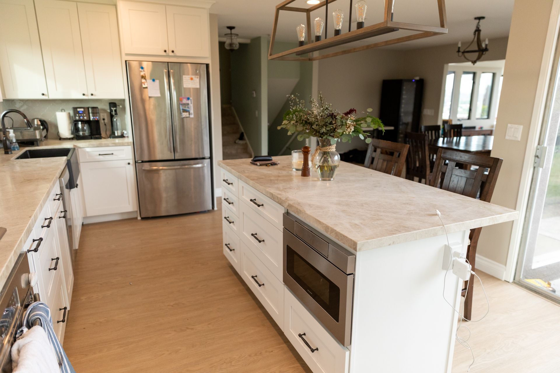 A kitchen with white cabinets , stainless steel appliances , and a large island.