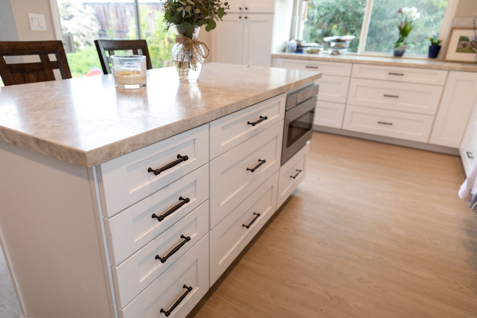 A kitchen with white cabinets and a large island in the middle.