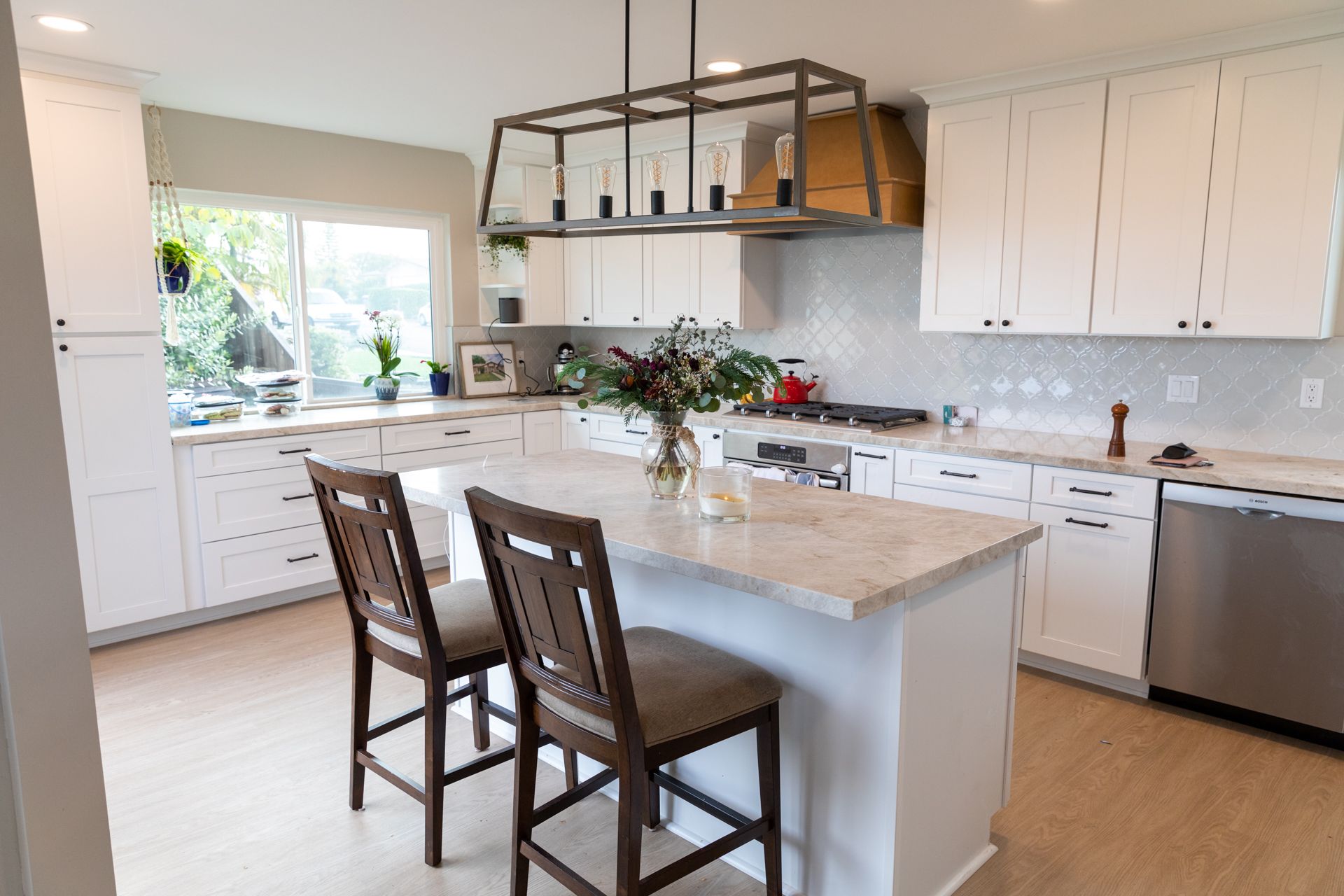 A kitchen with white cabinets , stainless steel appliances , and a large island.
