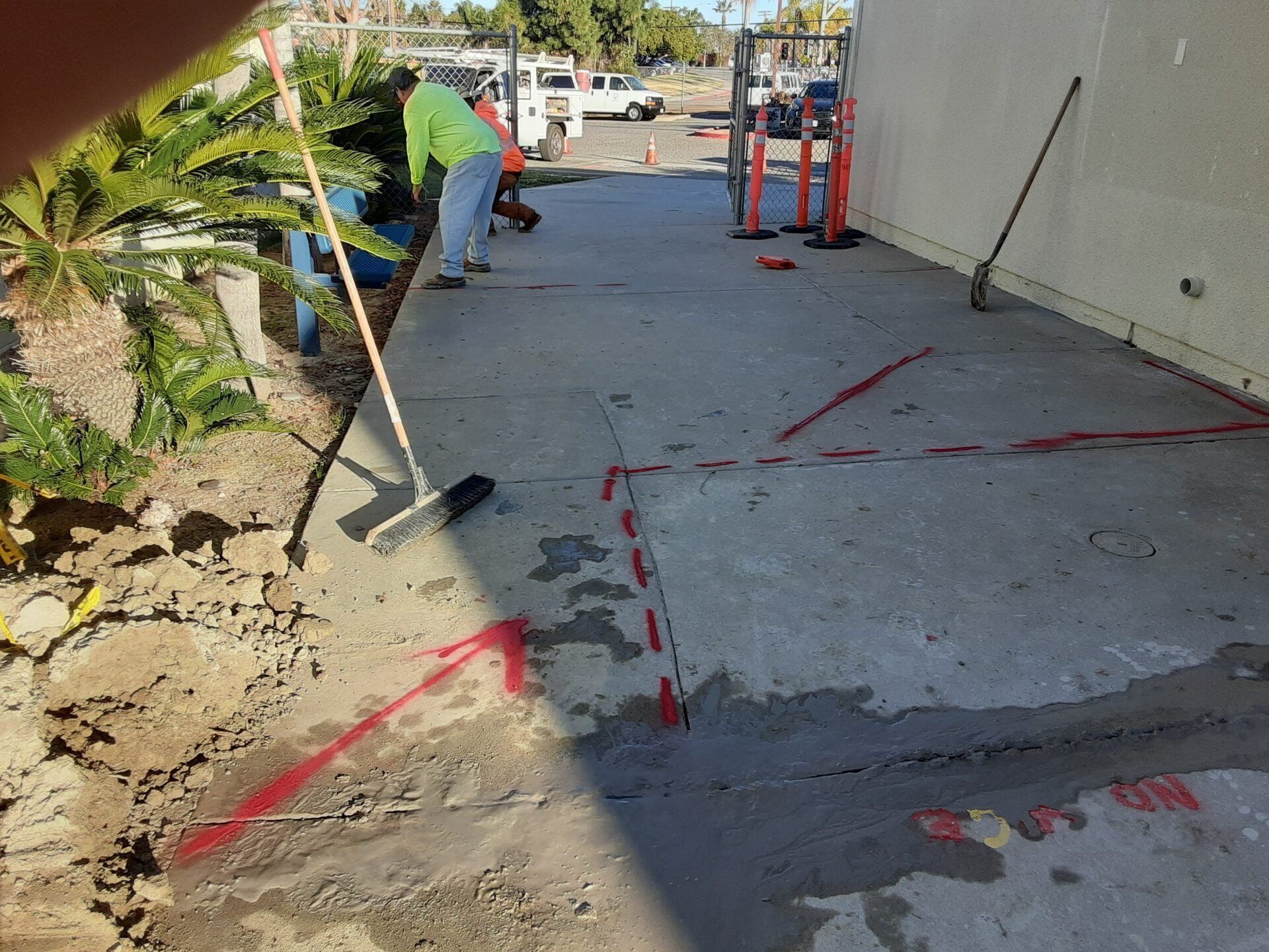 A man with a broom is working on a concrete sidewalk.
