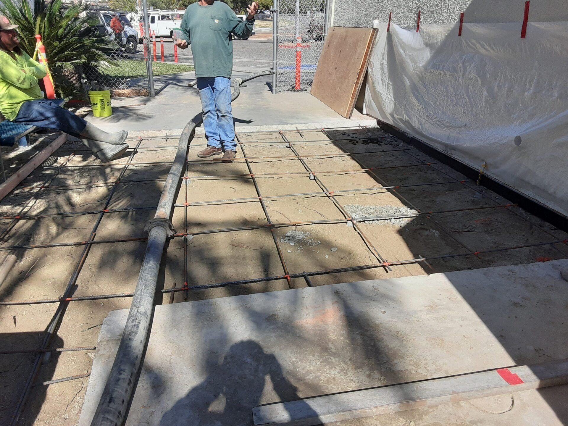 A man is standing on a sidewalk holding a hose.