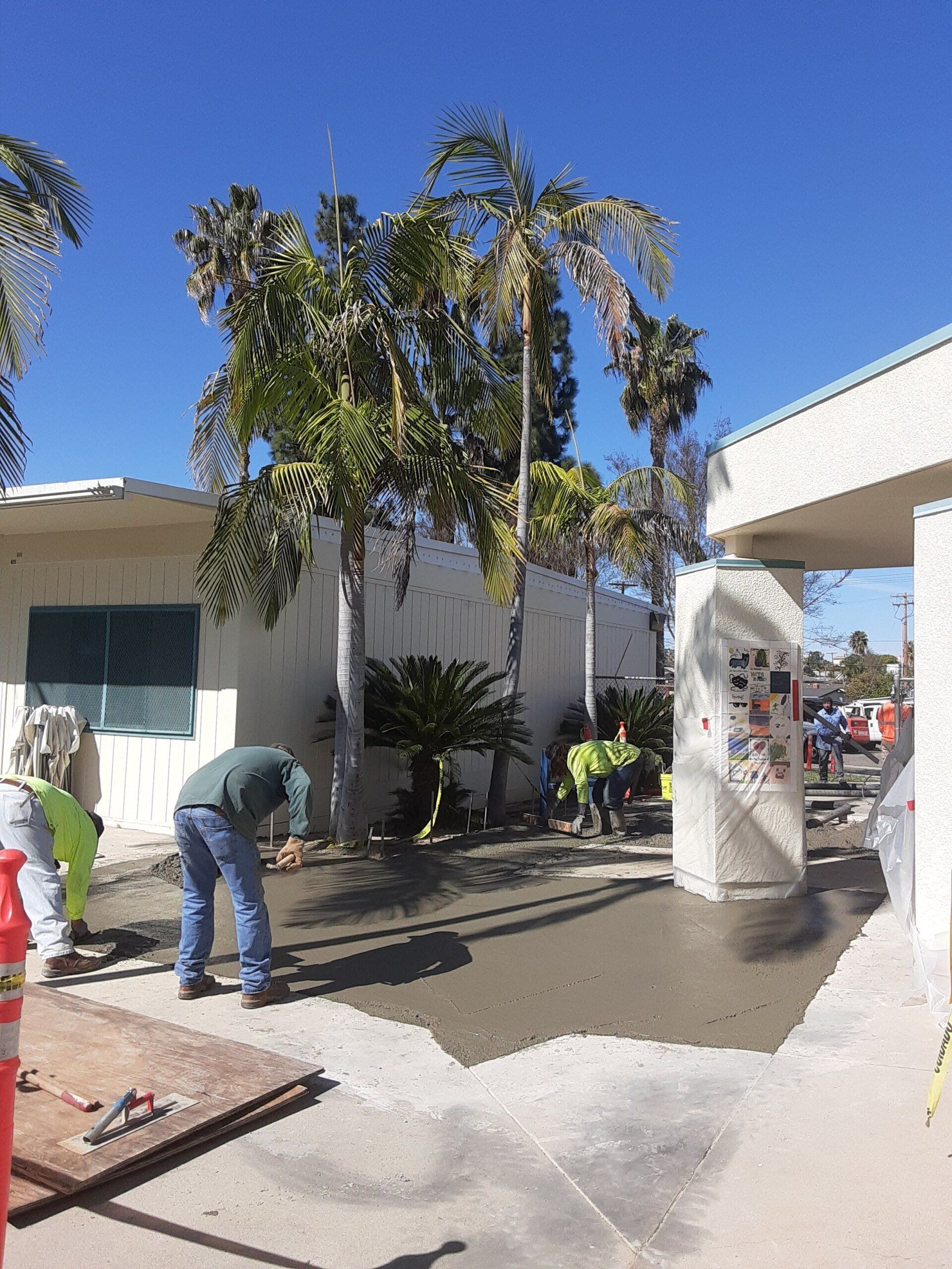 A group of construction workers are working on a sidewalk in front of a building