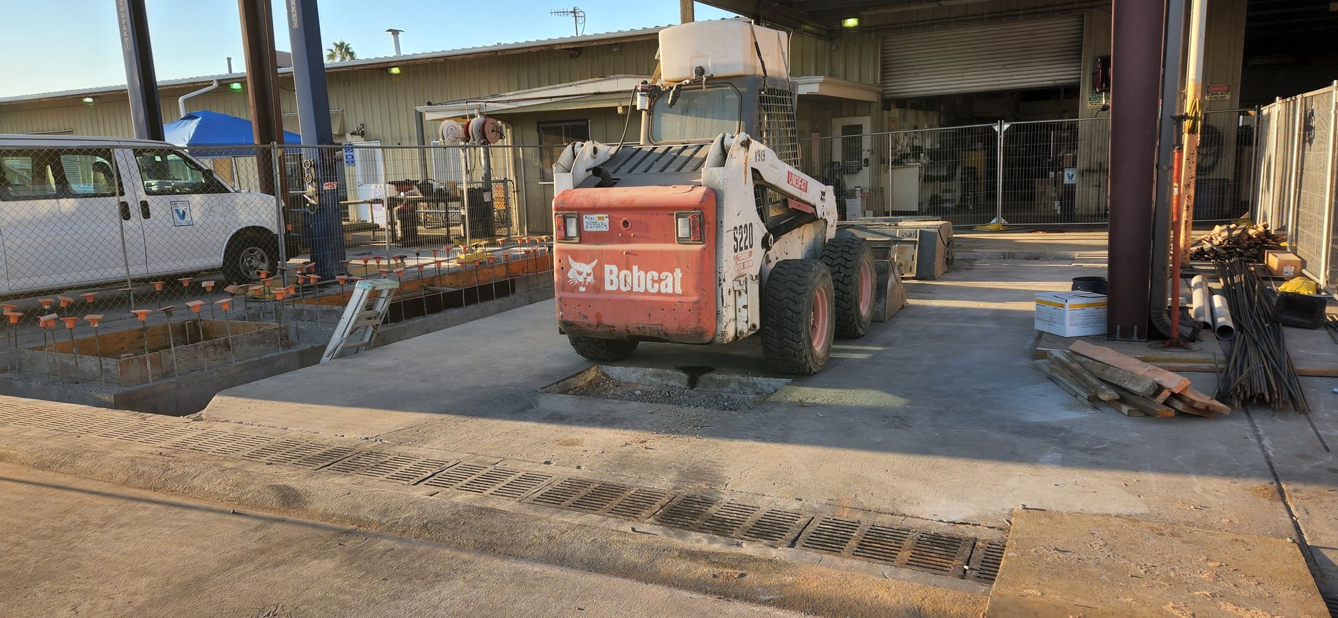A bobcat skid steer is parked in front of a building.