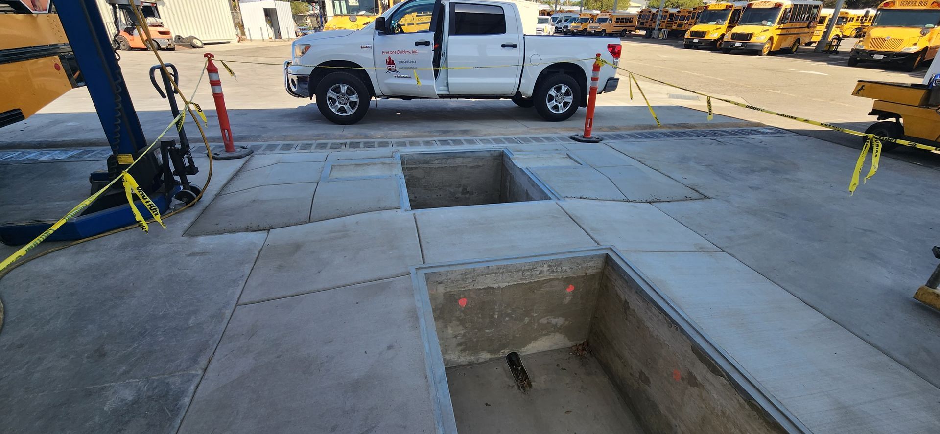 A white truck is parked in a parking lot next to a hole in the ground.