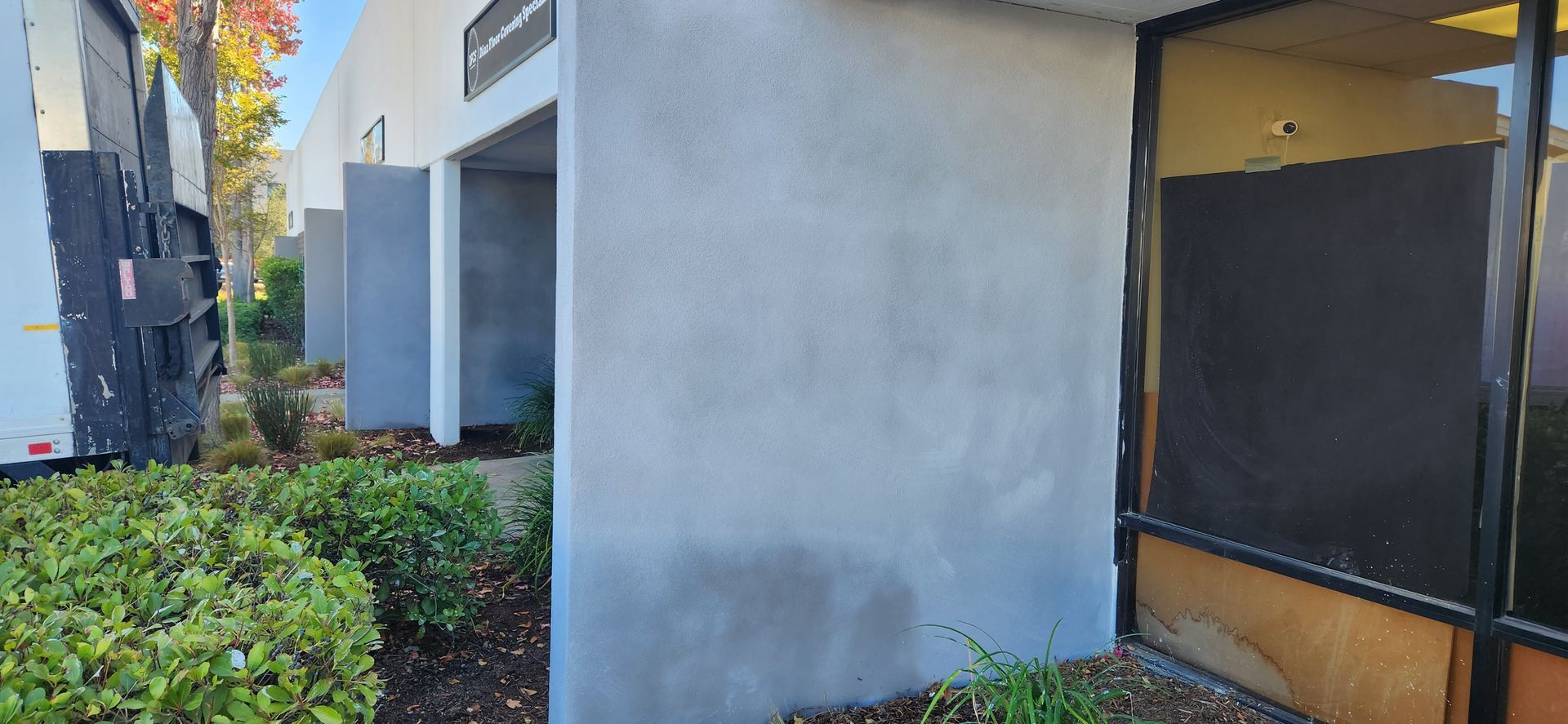 A concrete wall with a window in front of a building.