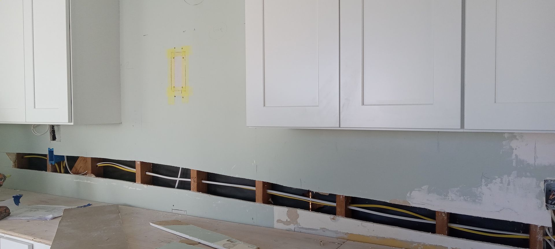 A kitchen with white cabinets and a black stripe on the wall.