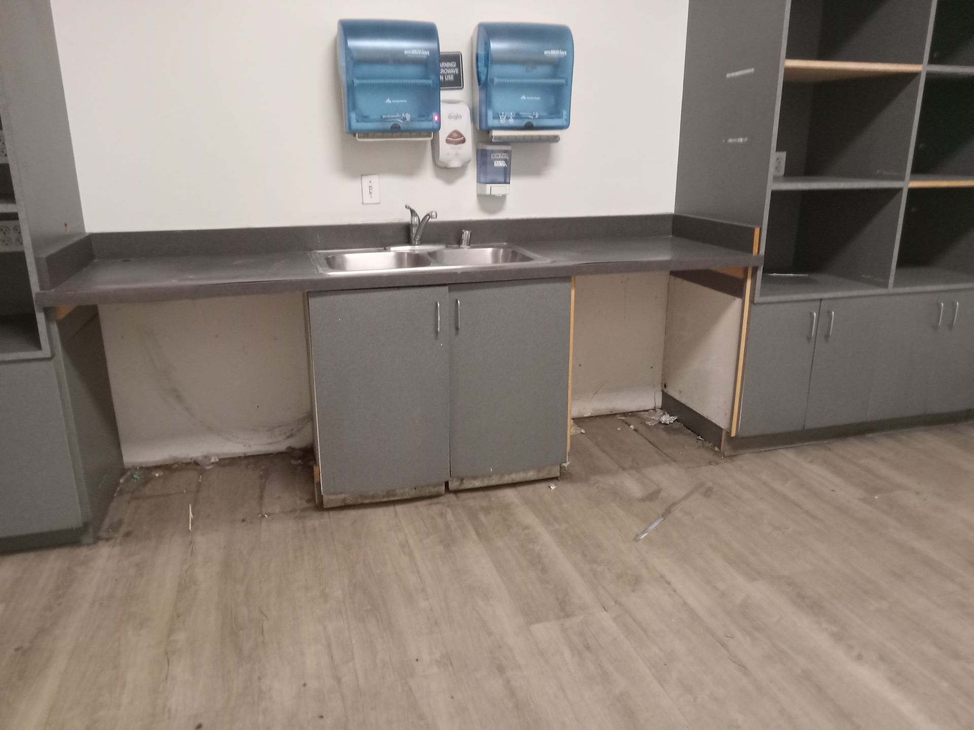 A kitchen with a sink and paper towels on the wall.