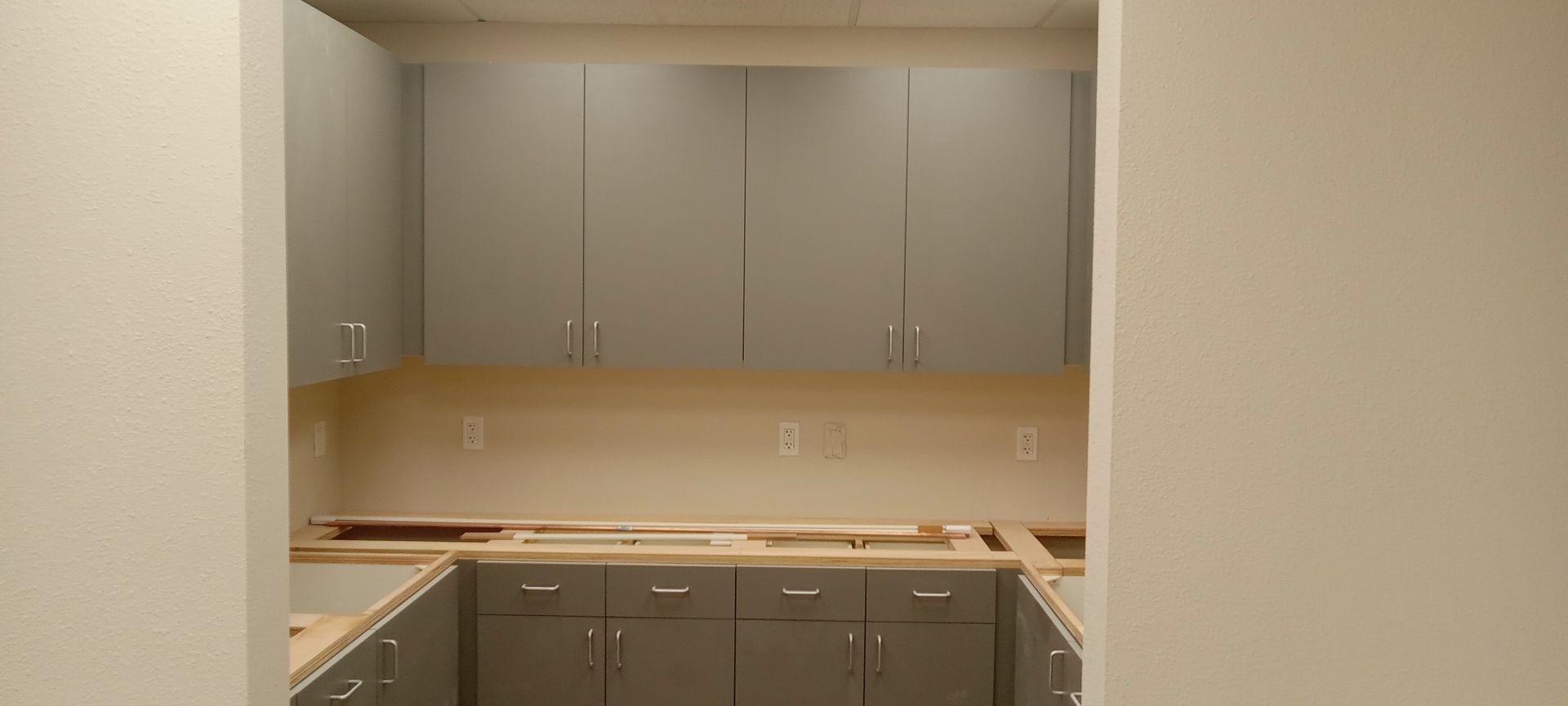 A kitchen with gray cabinets and wooden counter tops is being remodeled.