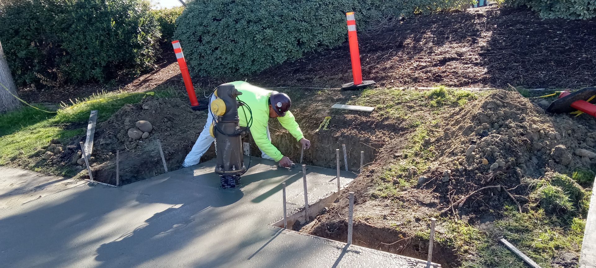 Two construction workers are working on a concrete driveway.