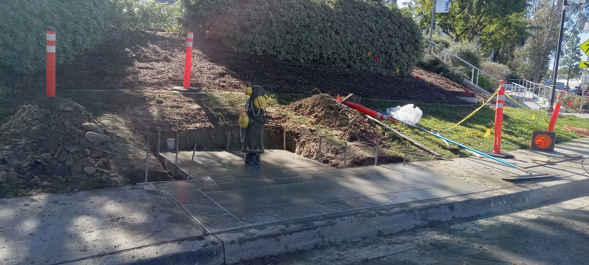 A pile of dirt is sitting on the side of the road next to a sidewalk.