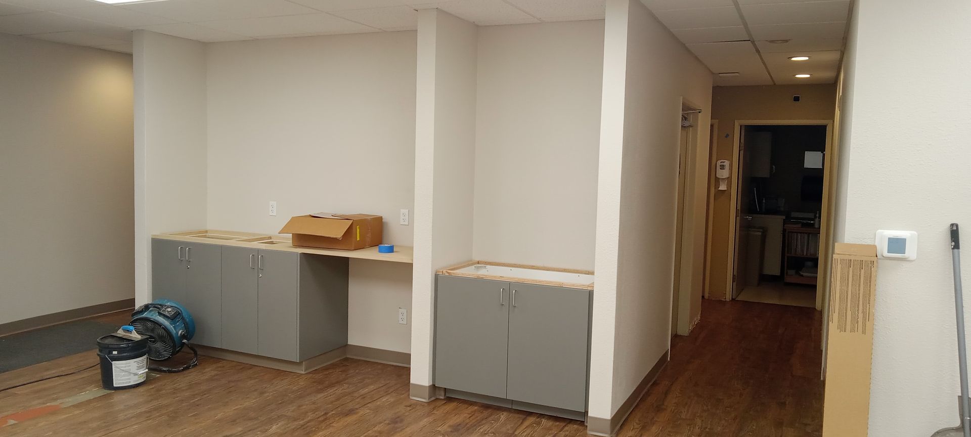 A room with a wooden floor and cabinets in it is being remodeled.