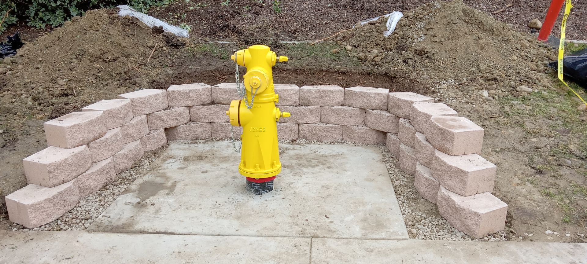 A yellow fire hydrant is sitting in the middle of a brick wall.
