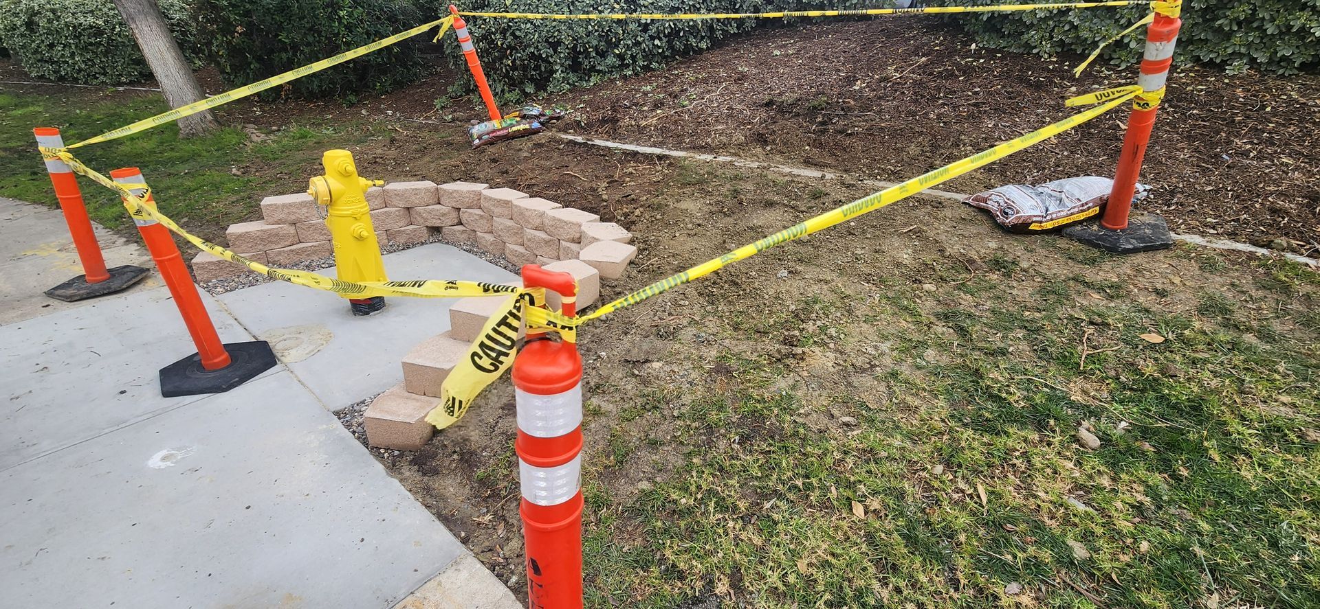 A fence with orange and white poles and yellow tape.