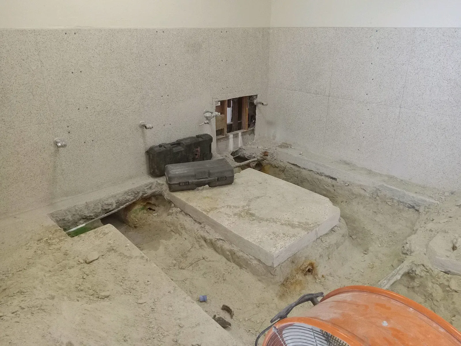 A bathroom under construction with a lot of sand on the floor.