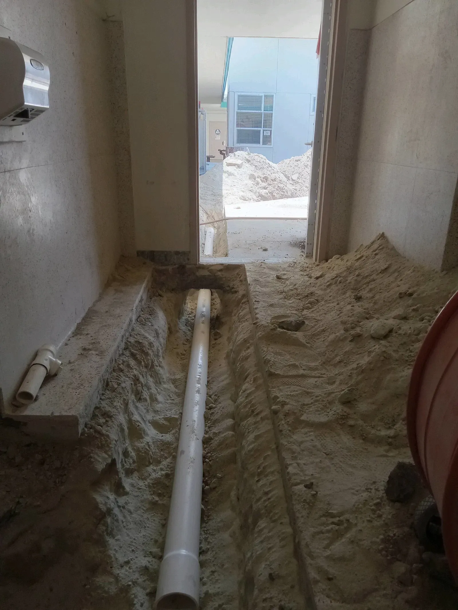 A pipe is laying in the dirt in a room.