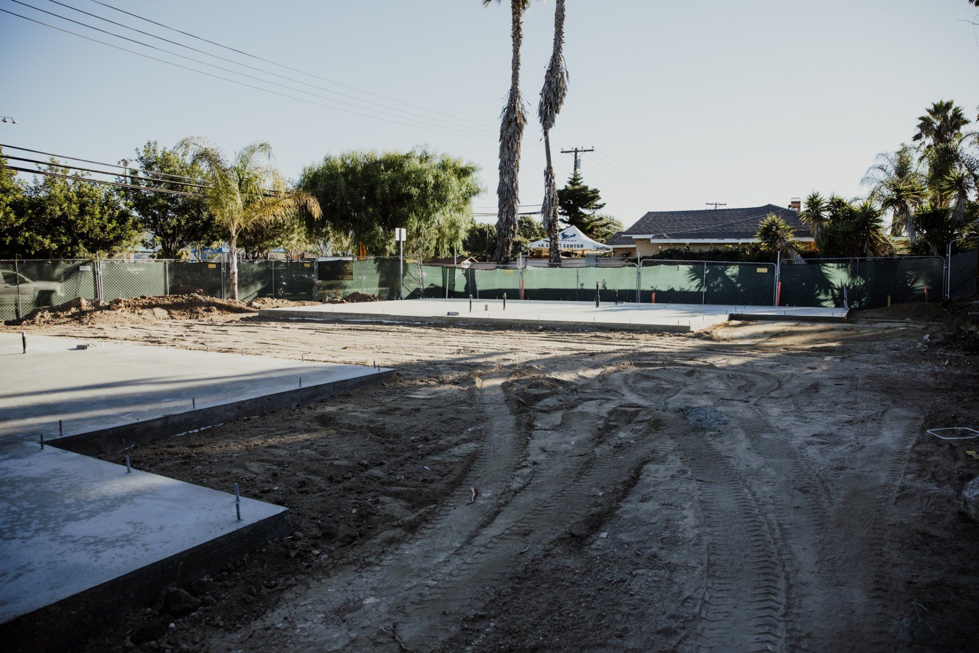 A dirt road leading to a house with palm trees in the background
