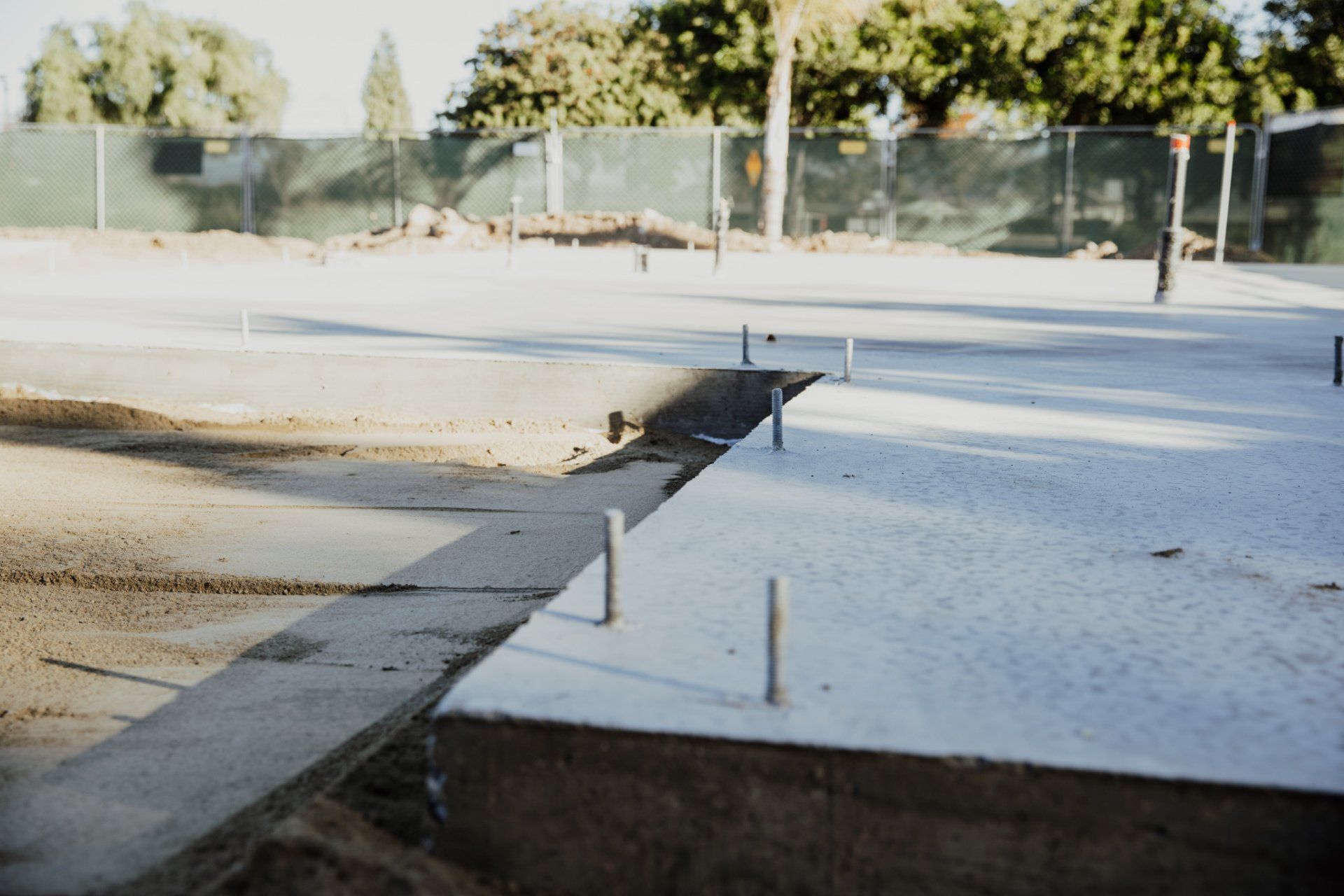A concrete floor with a fence in the background is being built.