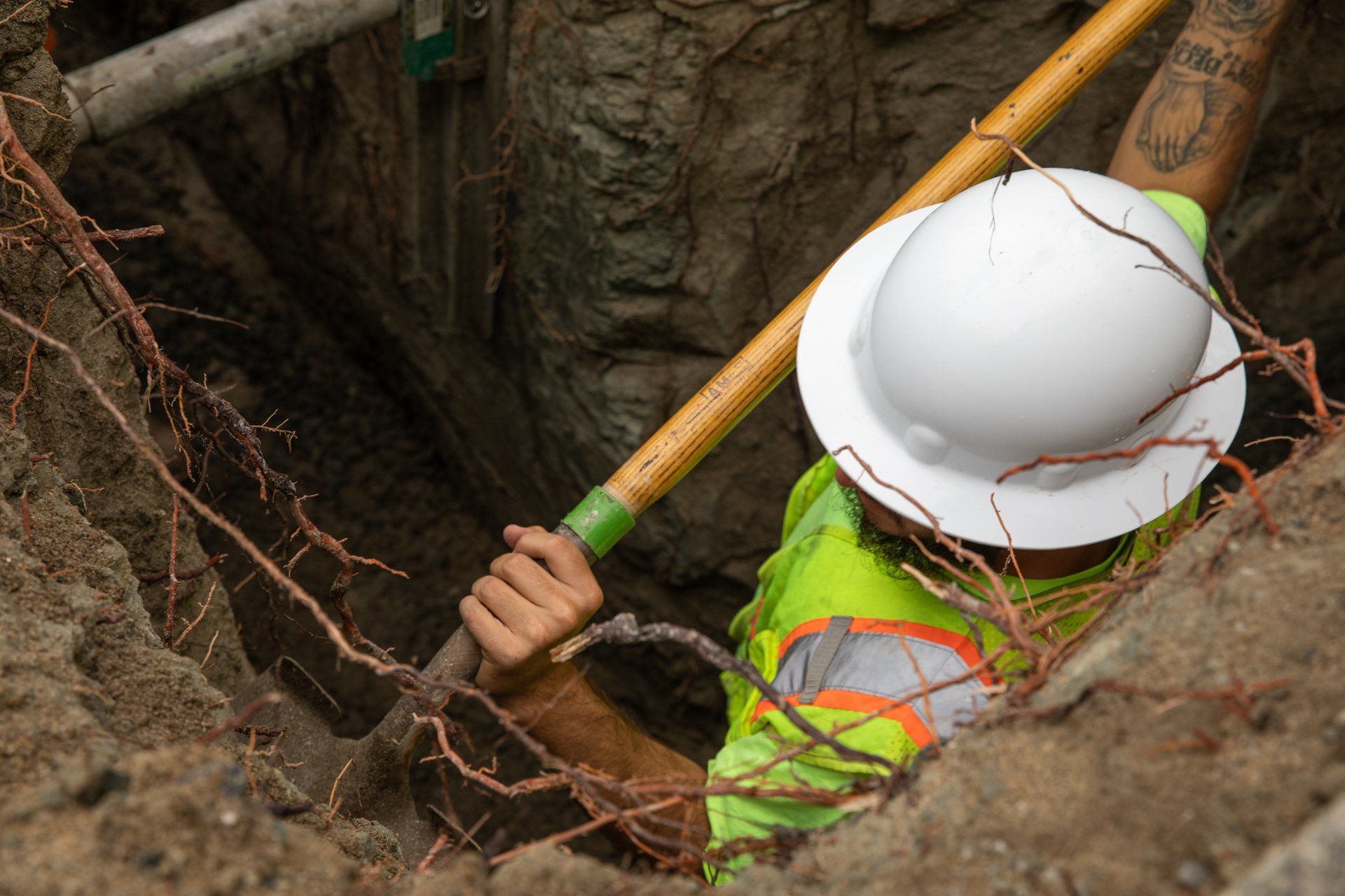 A man wearing a hard hat is digging in the dirt