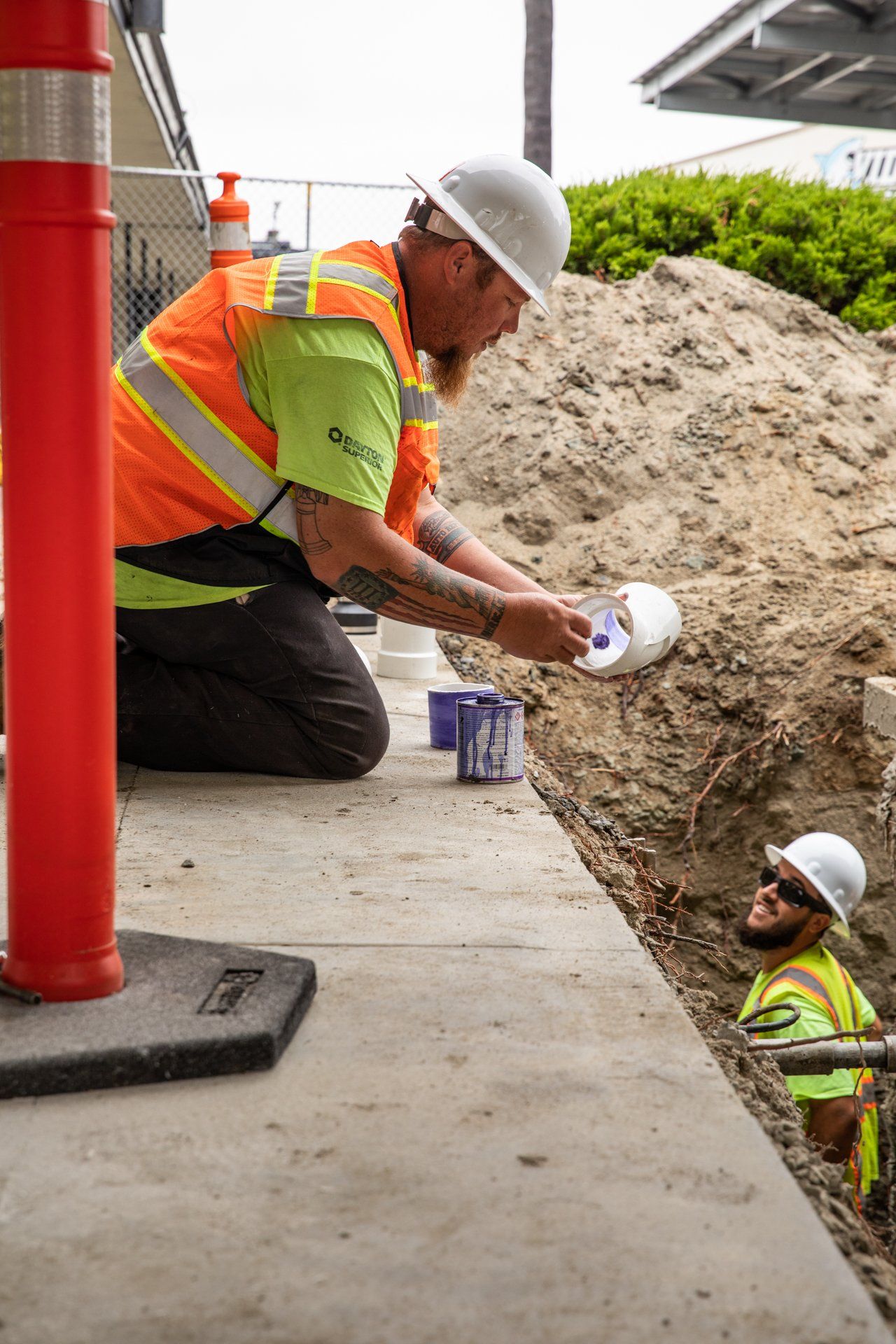 A man wearing a hard hat is kneeling down in the dirt