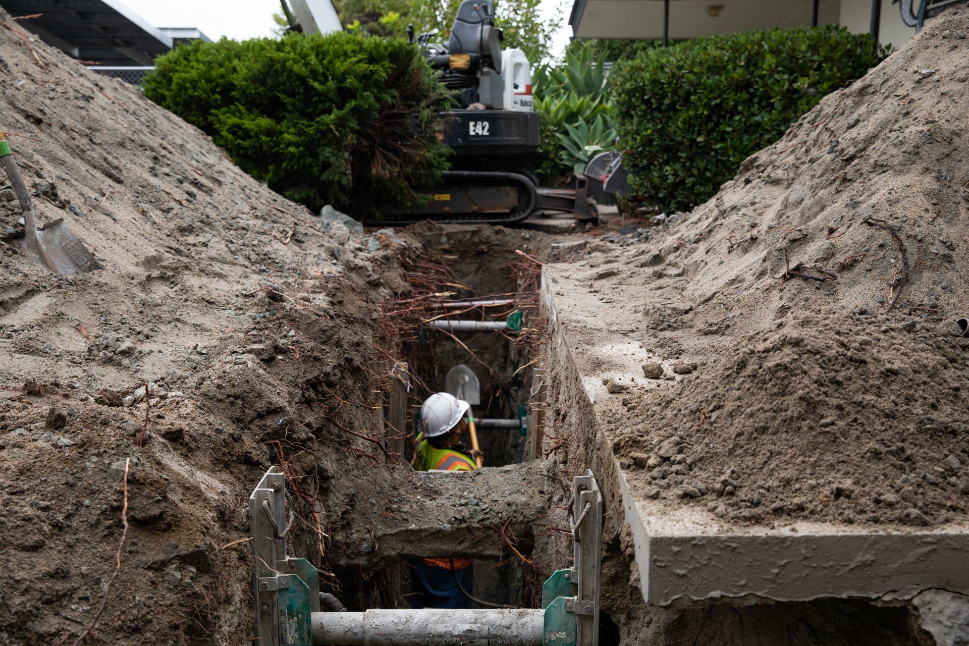 A man wearing a hard hat is working in a trench