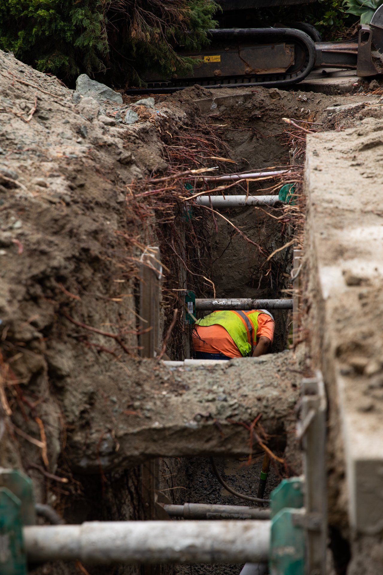 A construction worker is laying in the dirt in a trench
