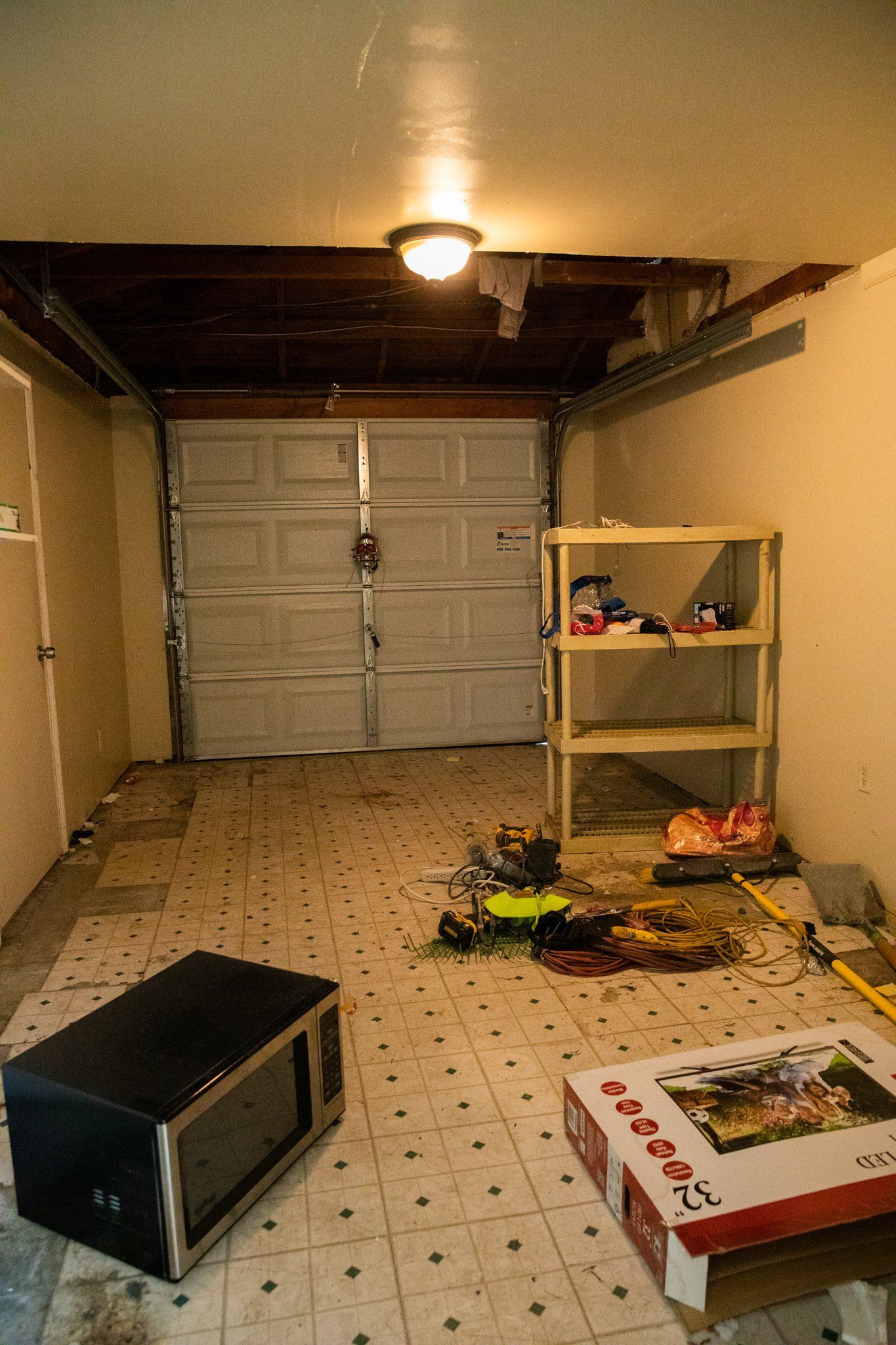 A microwave sits on the floor in a garage